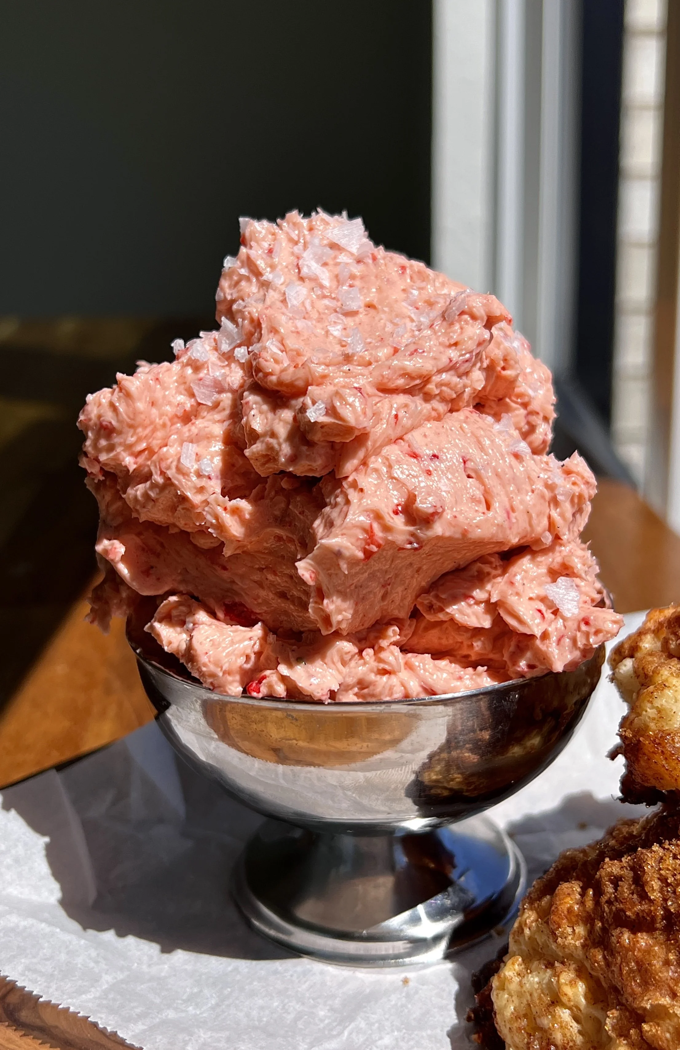 Cinnamon crunch sourdough cathead biscuits served warm with whipped strawberry honey butter, flaky sea salt, and a hot cup of coffee.