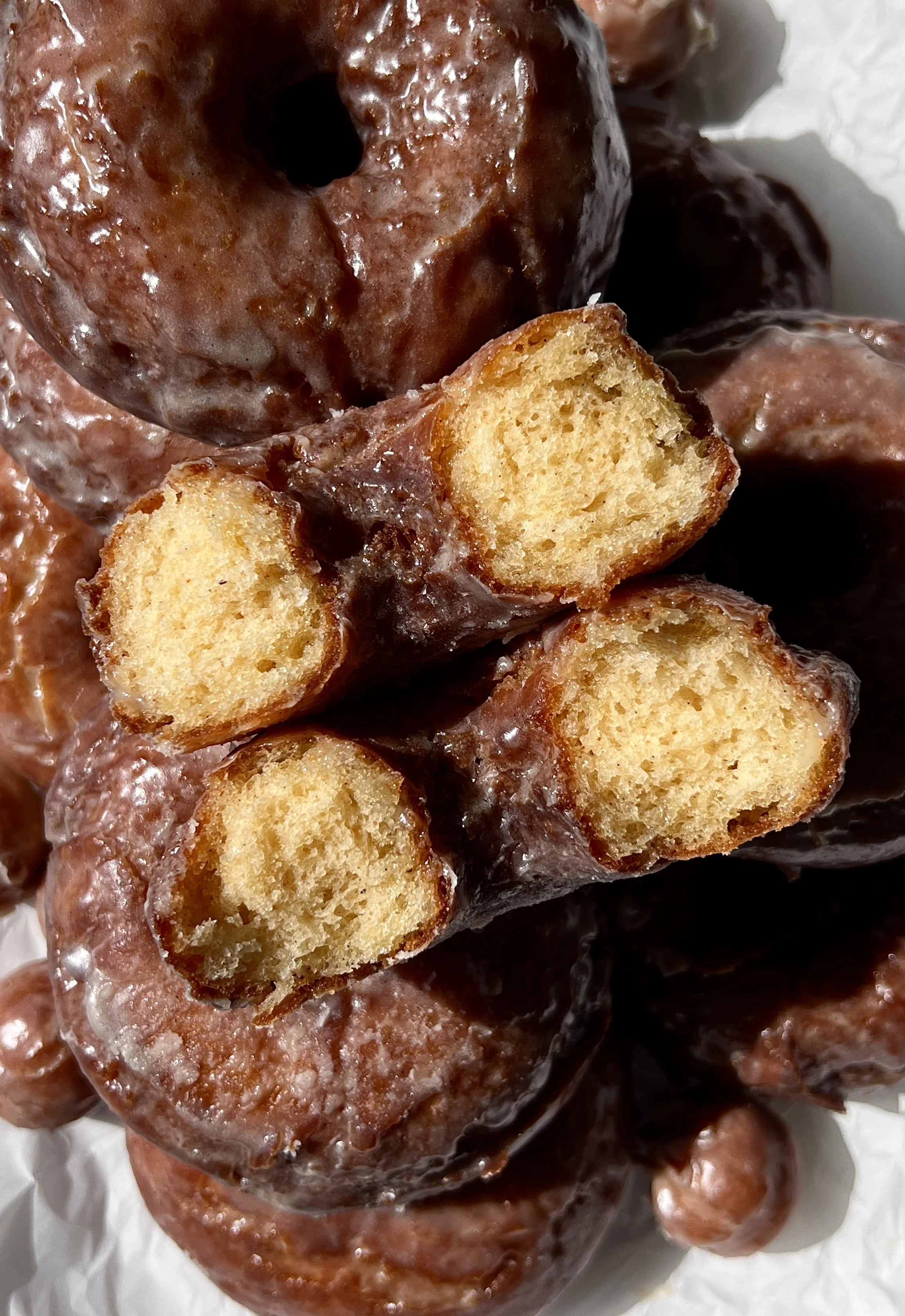 Close-up of a soft and fluffy old-fashioned sour cream donut with a beautifully golden and slightly crisp exterior coated in a silky vanilla bean glaze.