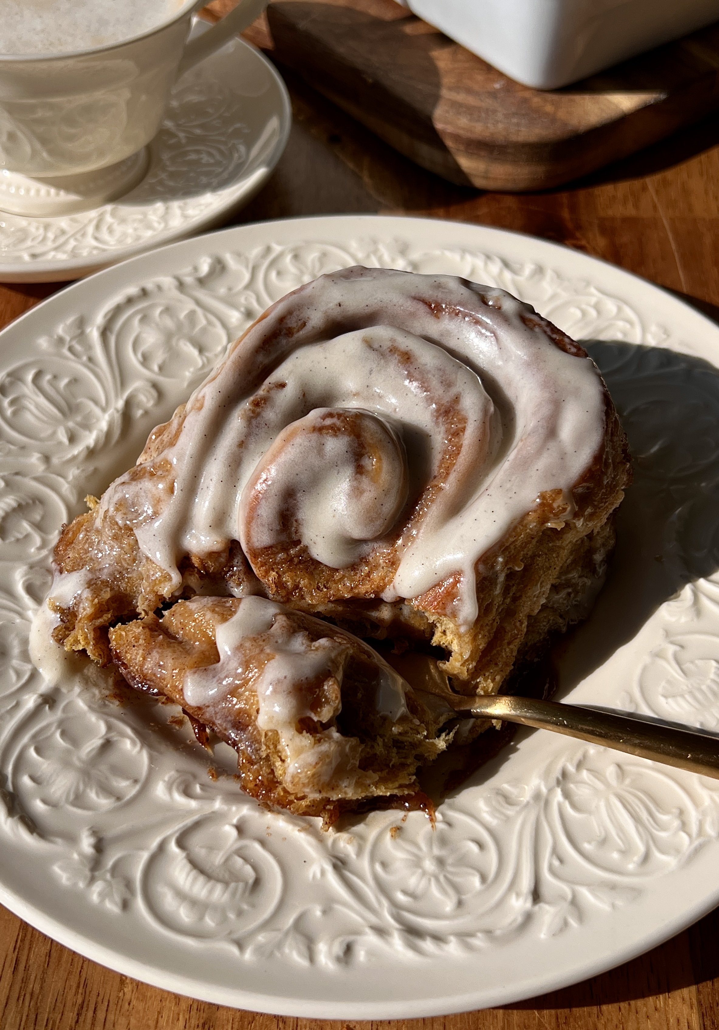Soft and fluffy homemade pumpkin cinnamon rolls with beautifully golden caramelized edges and a warming gooey pumpkin spice cinnamon filling finished with classic cream cheese frosting served warm with a hot cup of coffee.