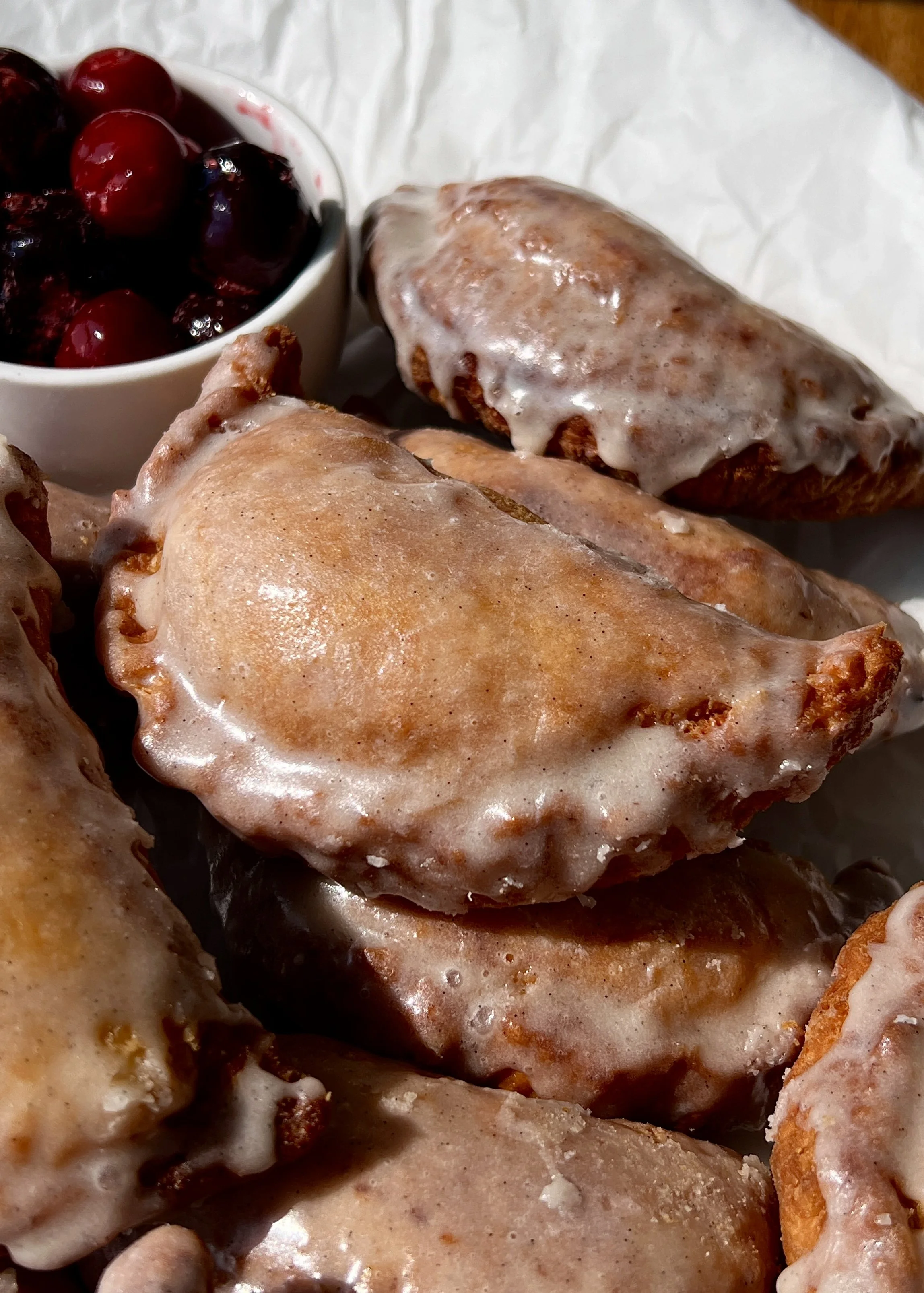 Close-up of a golden fried cherry hand pie with a flaky buttery crust and sweet and tart homemade cherry pie filling bursting throughout.