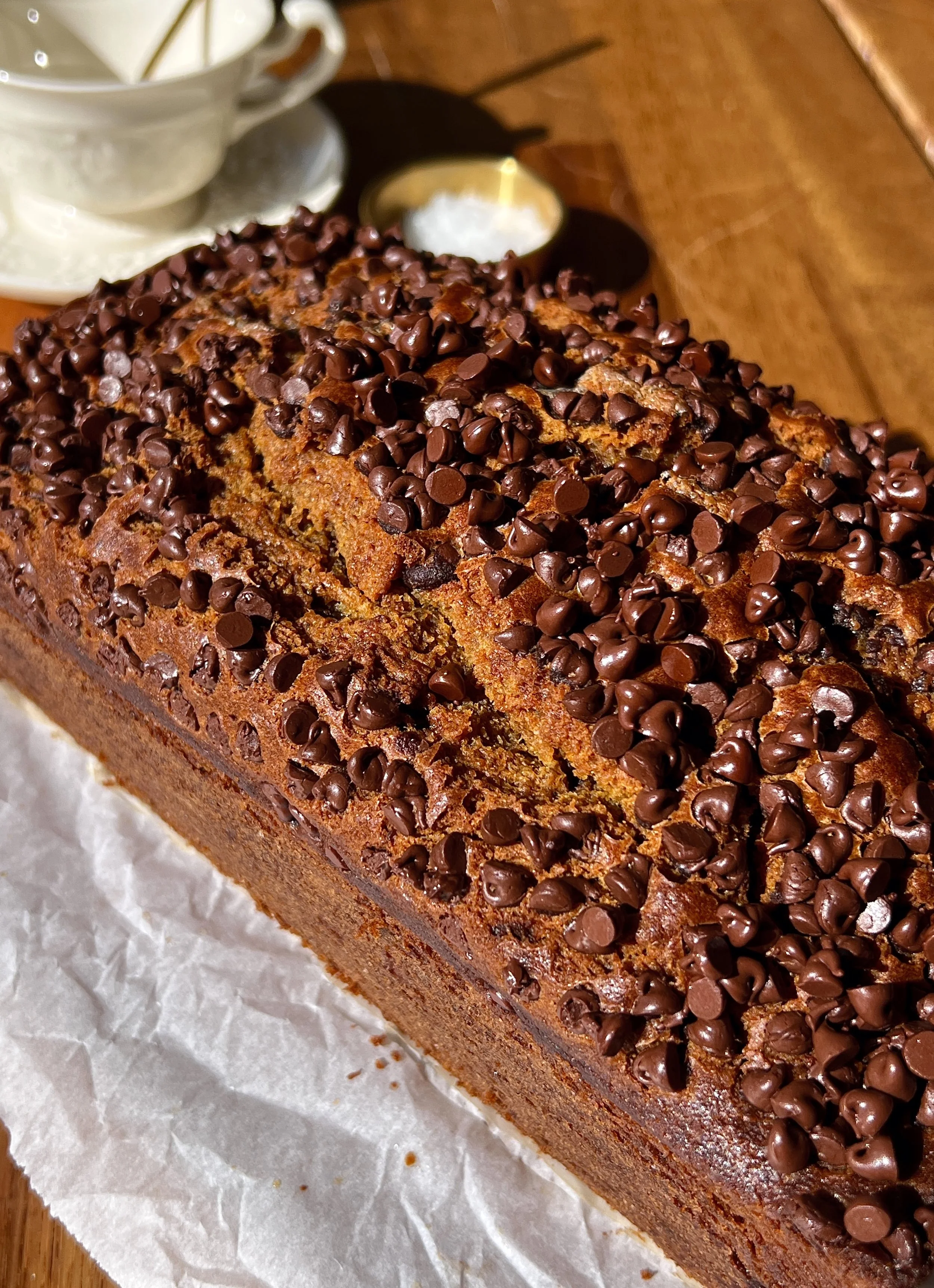 Close-up of a slice of brown butter chocolate chip pumpkin bread showing the soft tender crumb with melty chocolate chips throughout and a perfectly golden and slightly crisp exterior.