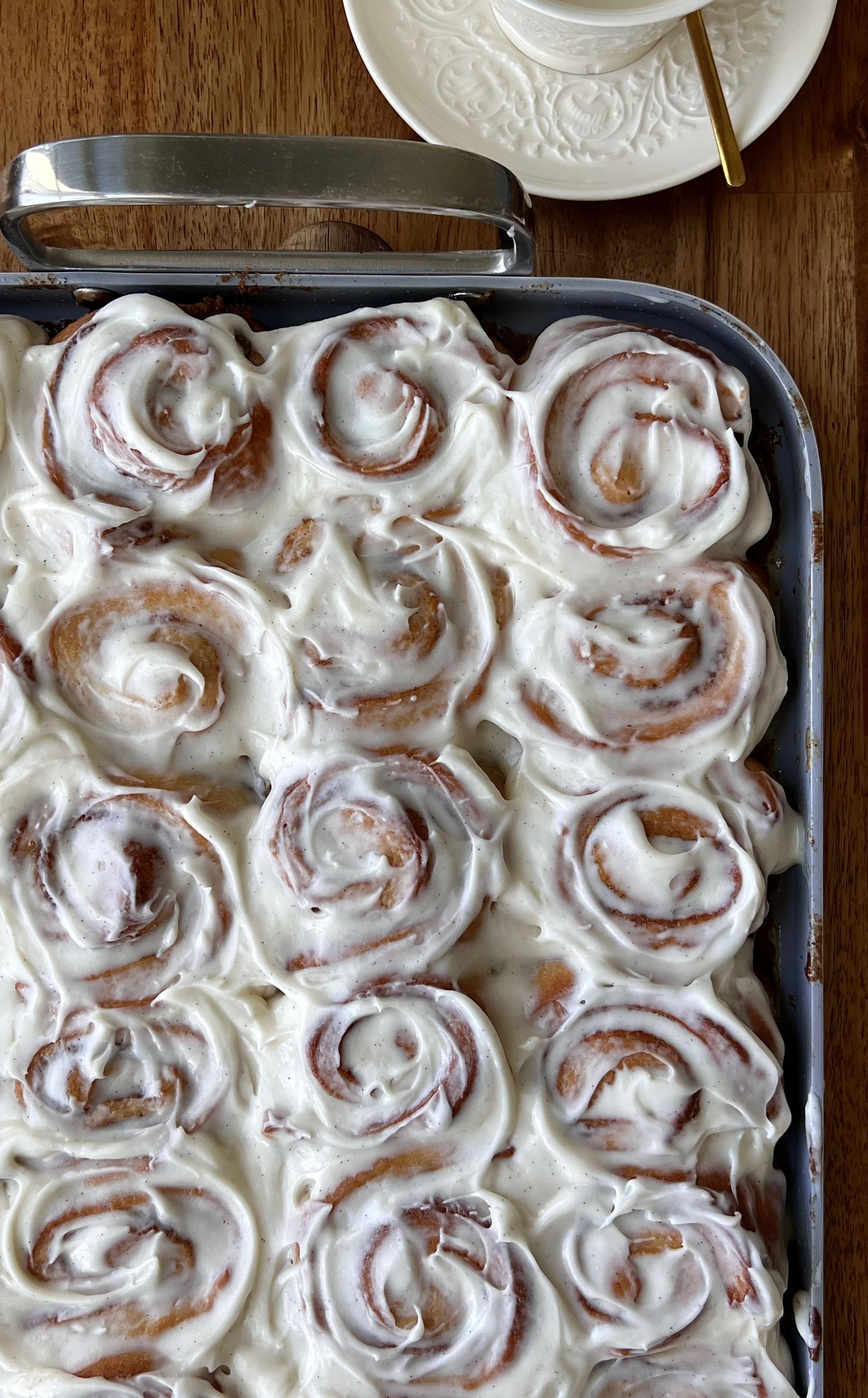Close-up of Mini Classic Cinnamon Rolls topped with cream cheese frosting and served warm with coffee