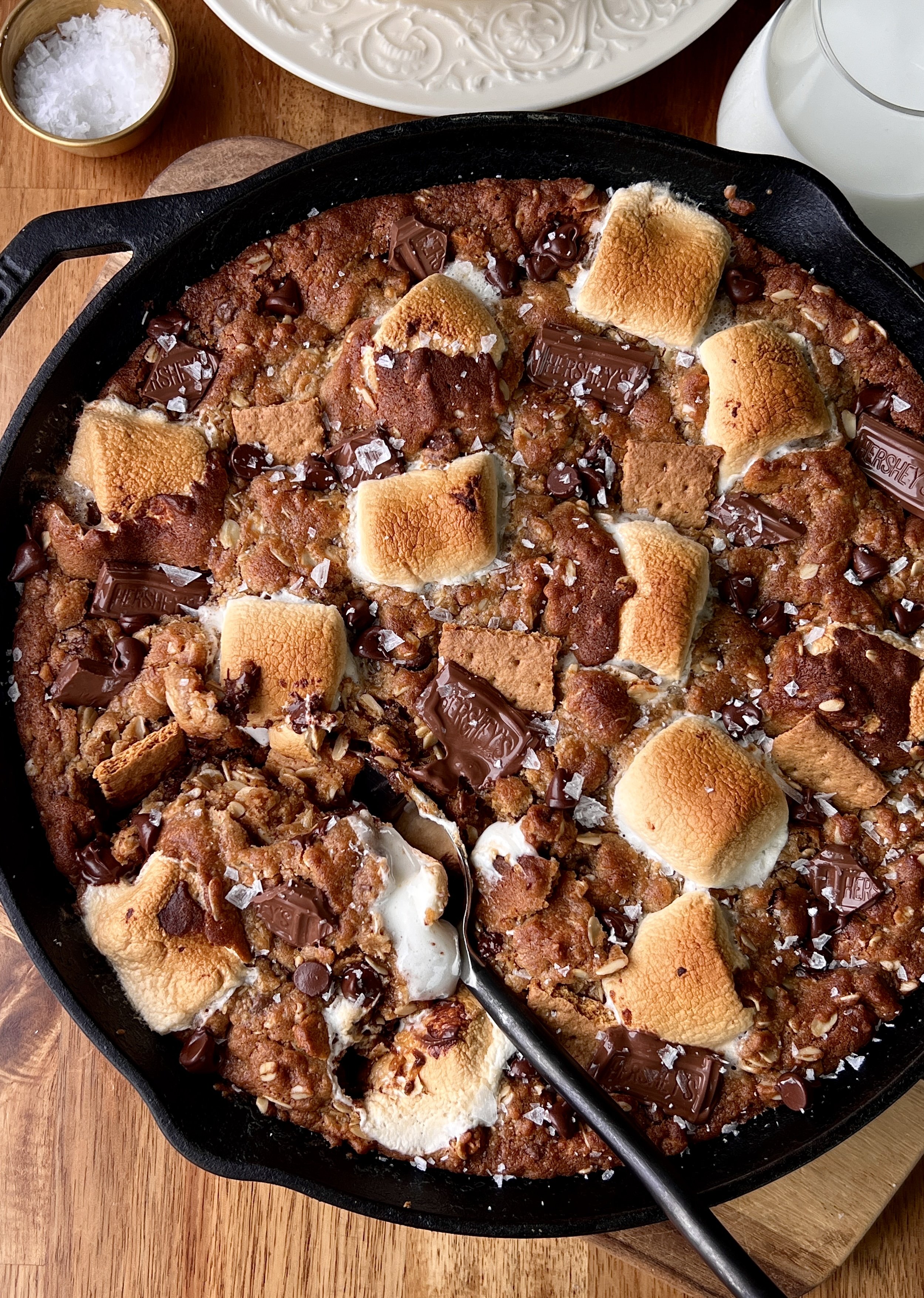 Peanut butter s'mores oatmeal cookie skillet with melty chocolate, gooey toasted marshmallows, and crushed graham crackers served warm with a scoop of vanilla ice cream and flaky sea salt.