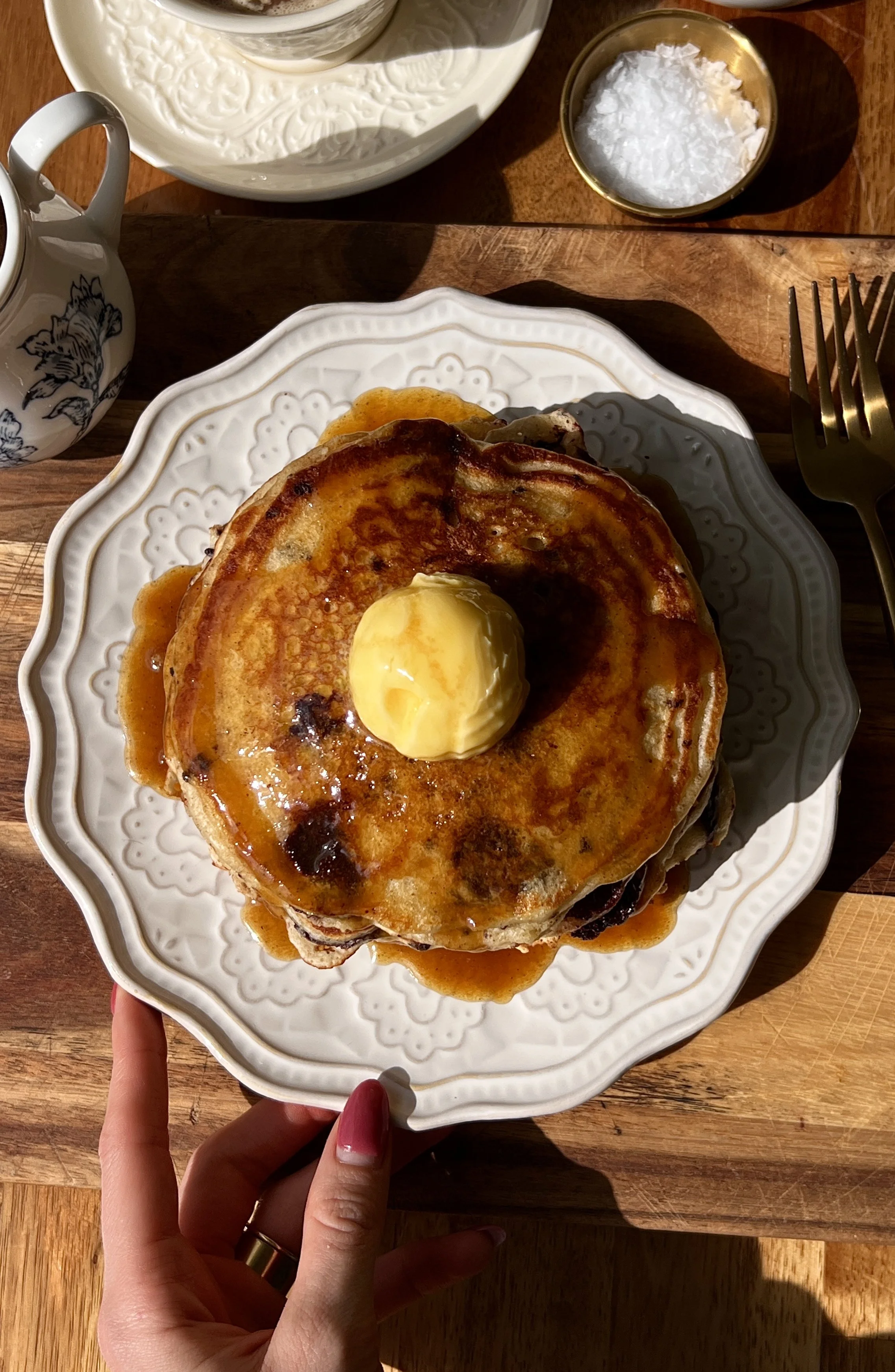 Soft and fluffy brown butter chocolate chip pancakes served warm with a pat of butter, maple espresso buttermilk syrup, and a hot cup of coffee.