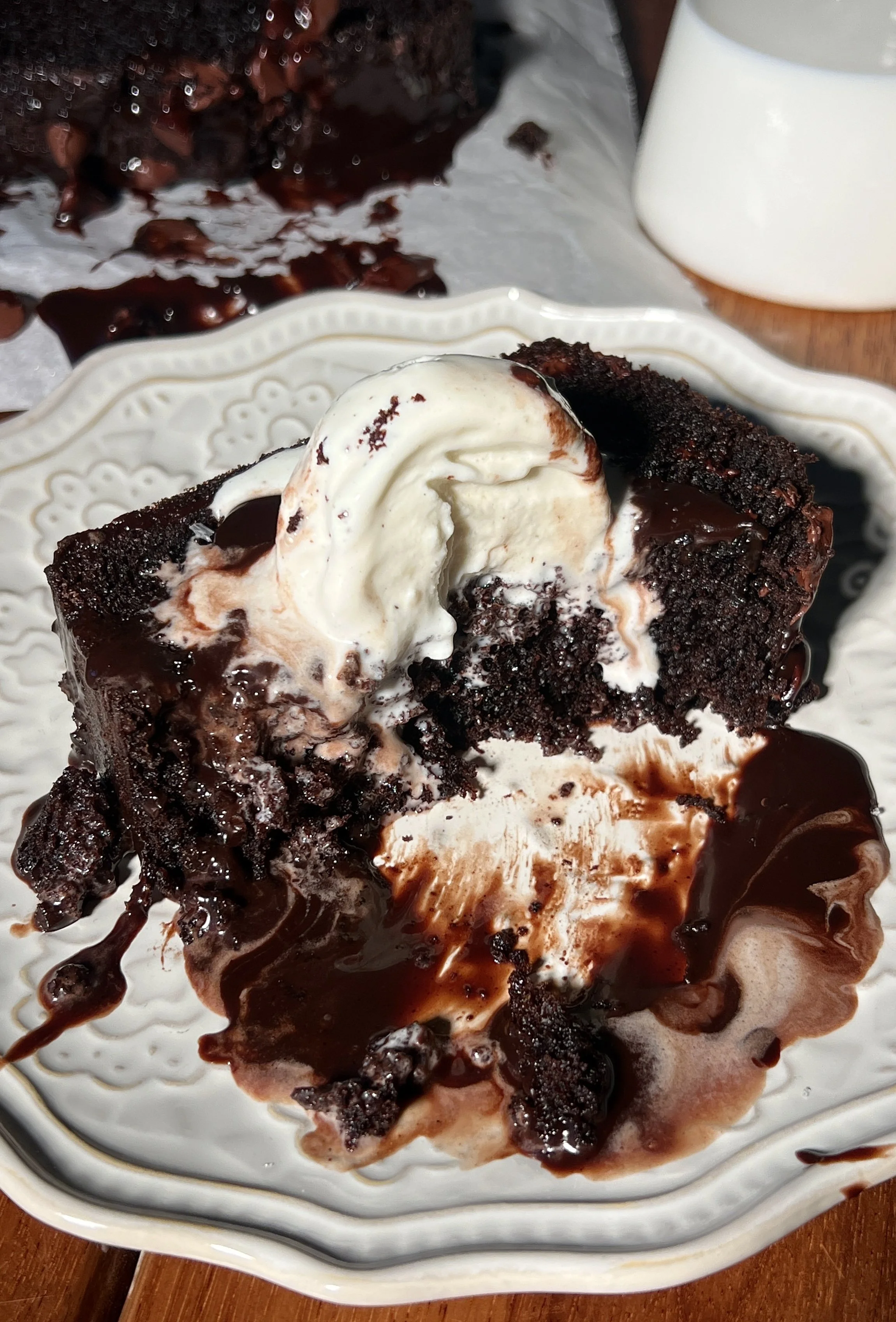 A warm and fudgy brown butter hot fudge brownie loaf with crisp edges, a gooey chocolate center, melty hot fudge sauce, vanilla ice cream, and flaky sea salt on top.