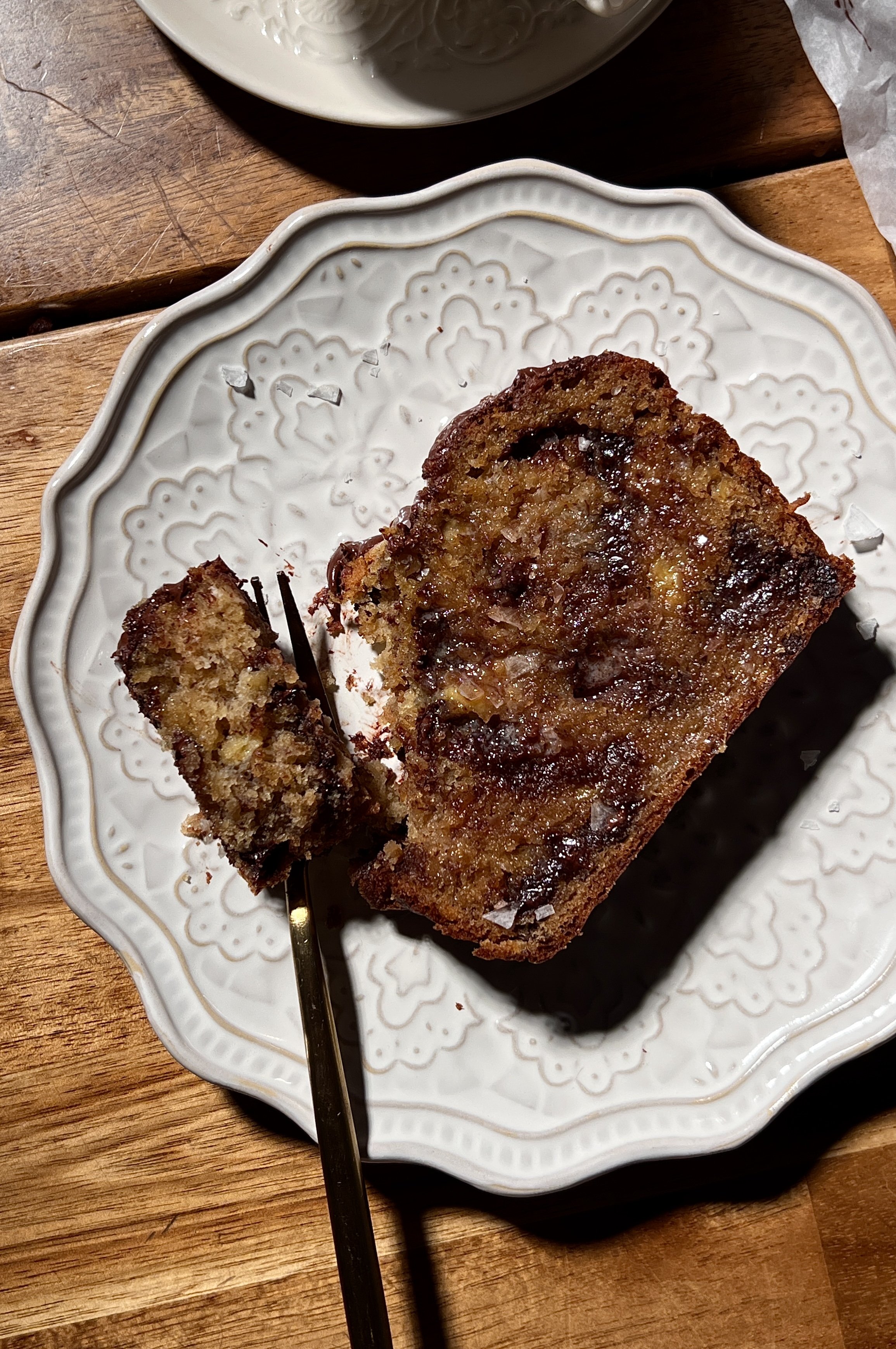 Brown butter banana bread loaf with melty chocolate chips, baked until golden, sliced and served warm with butter, flaky sea salt, and a cup of coffee.