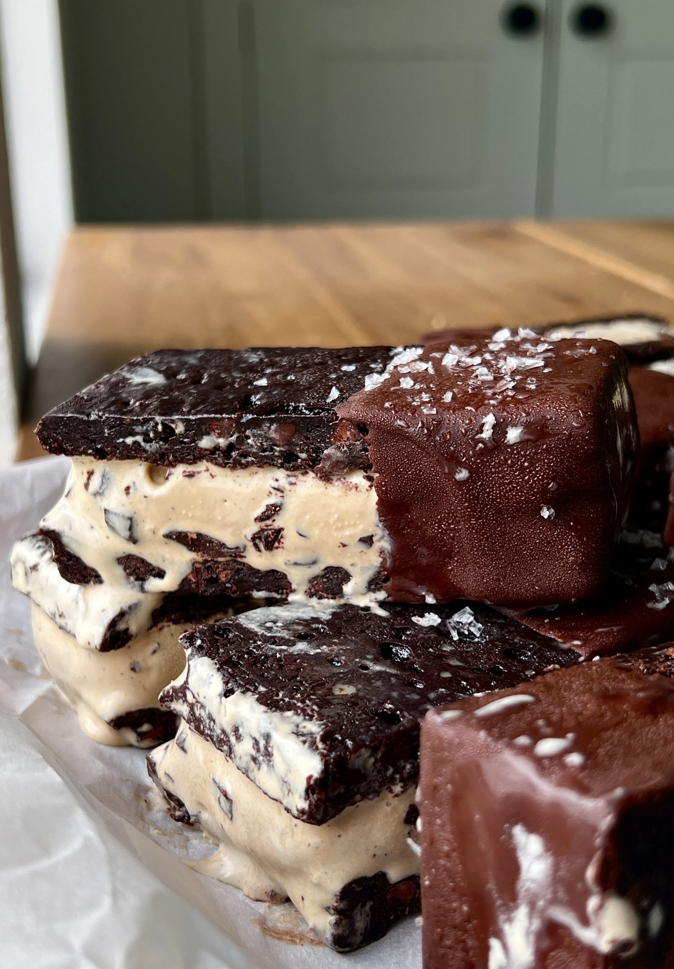 Close-up of a brownie ice cream sandwich showing the fudgy brownie layers with rich and creamy coffee chip ice cream and chocolate chunks throughout dipped in chocolate.