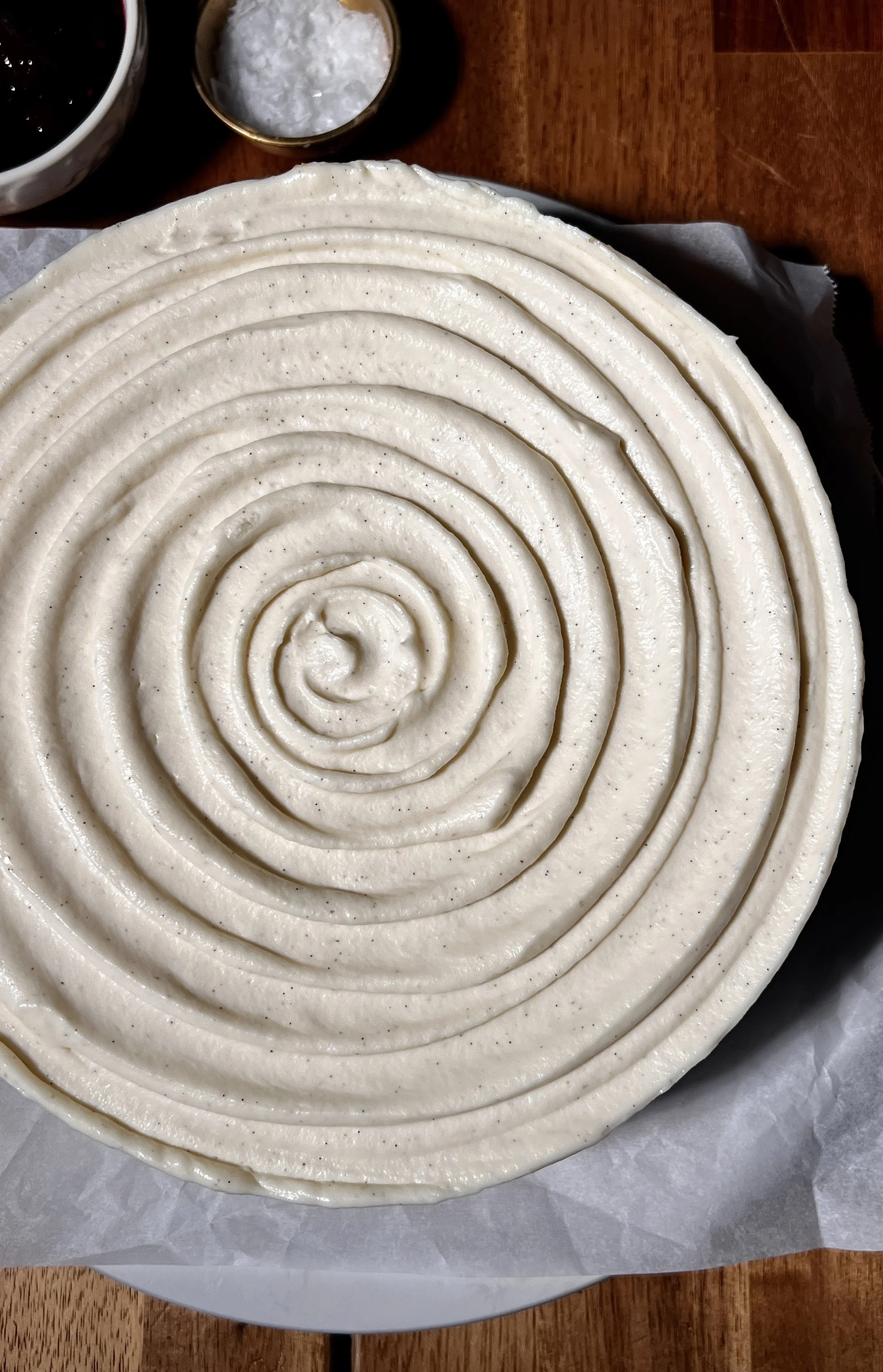 Creamy vanilla bean cheesecake with a buttery graham cracker crust, topped with a smooth layer of white chocolate mousse and finished with a glossy berry compote on top.