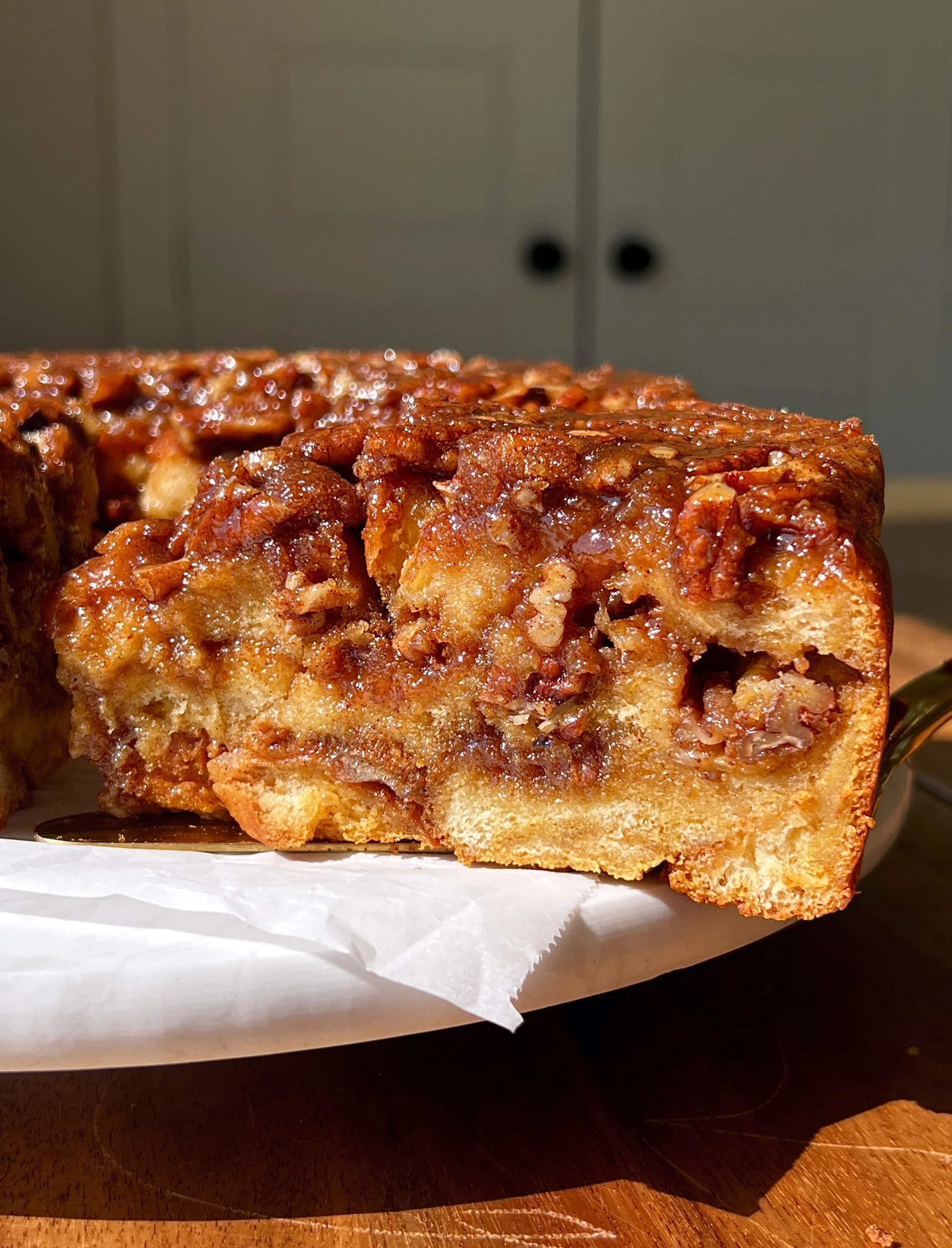 Close-up of pecan sticky bun pumpkin bread pudding showing the soft buttery brioche soaked in spiced pumpkin custard with a warming gooey sticky pecan filling swirled and layered throughout.