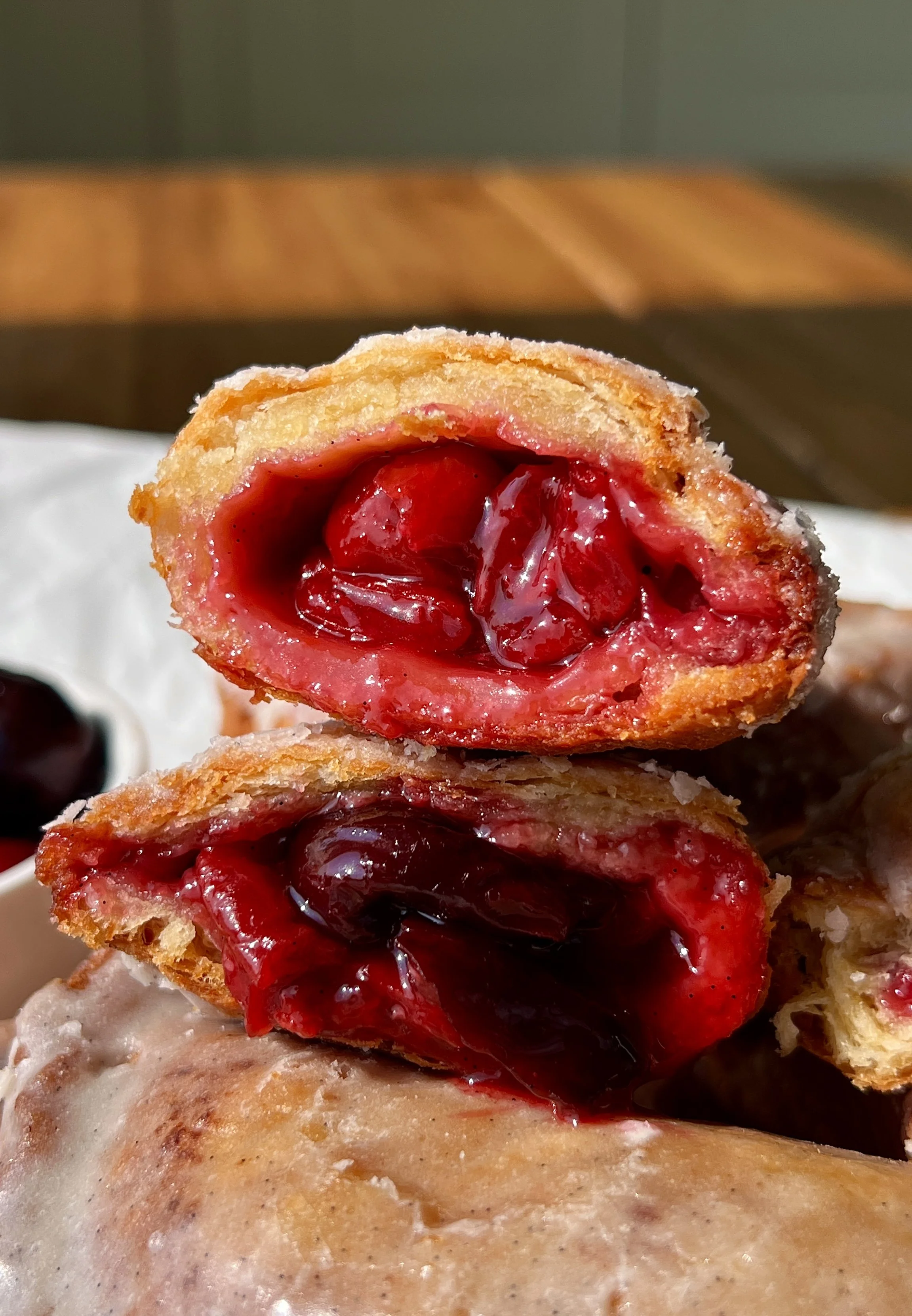 Close-up of a golden fried cherry hand pie with a flaky buttery crust and sweet and tart homemade cherry pie filling bursting throughout.