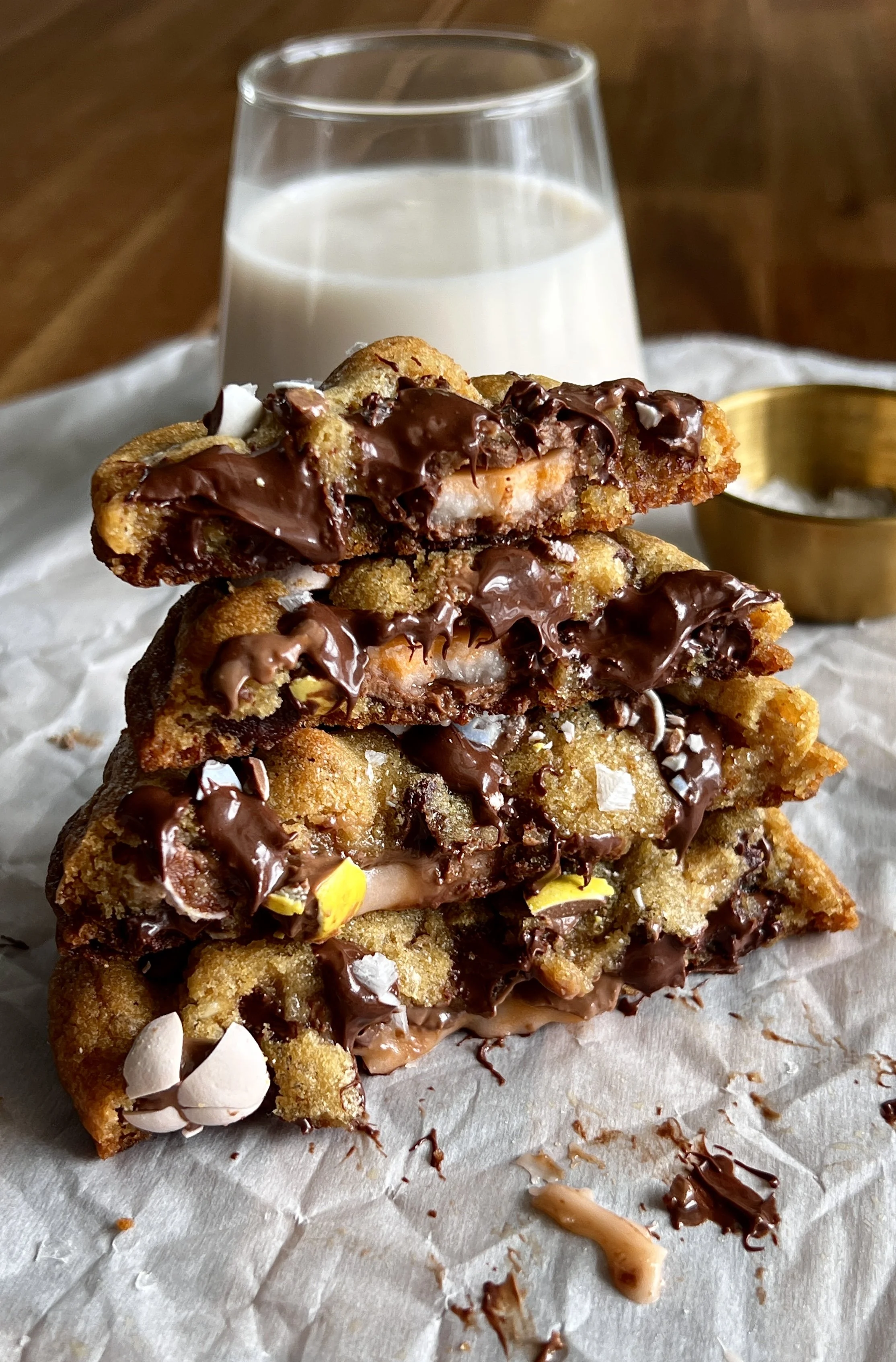 Brown butter Cadbury Creme Egg chocolate chip cookies with gooey centers, crisp edges, melty chocolate chips, crushed mini eggs, and a Creme Egg center, served with flaky sea salt and milk.