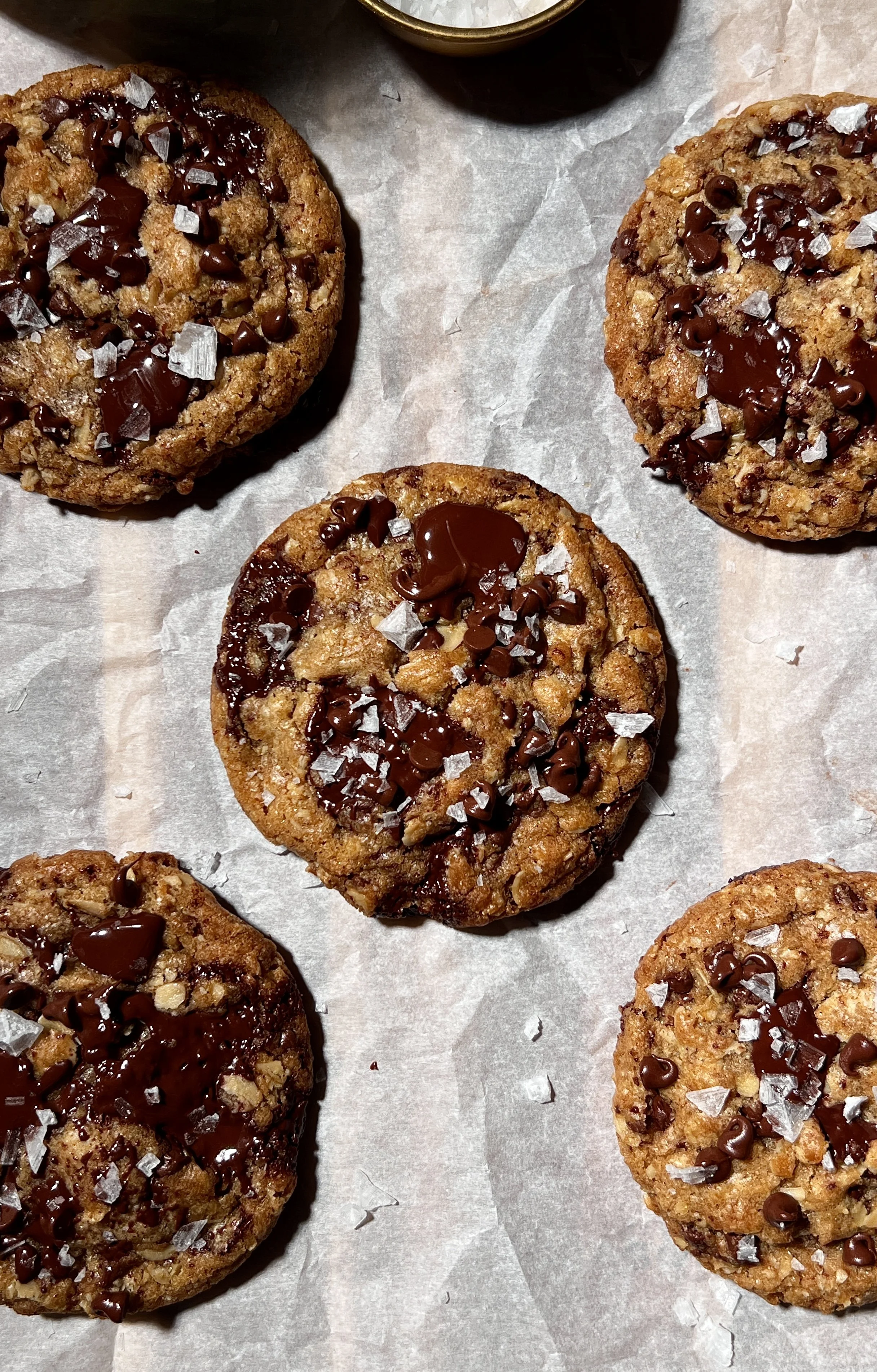 Brown butter oatmeal chocolate chip cookies with crisp golden edges and gooey centers, studded with melty chocolate chips and finished with flaky sea salt, served warm with a glass of milk.