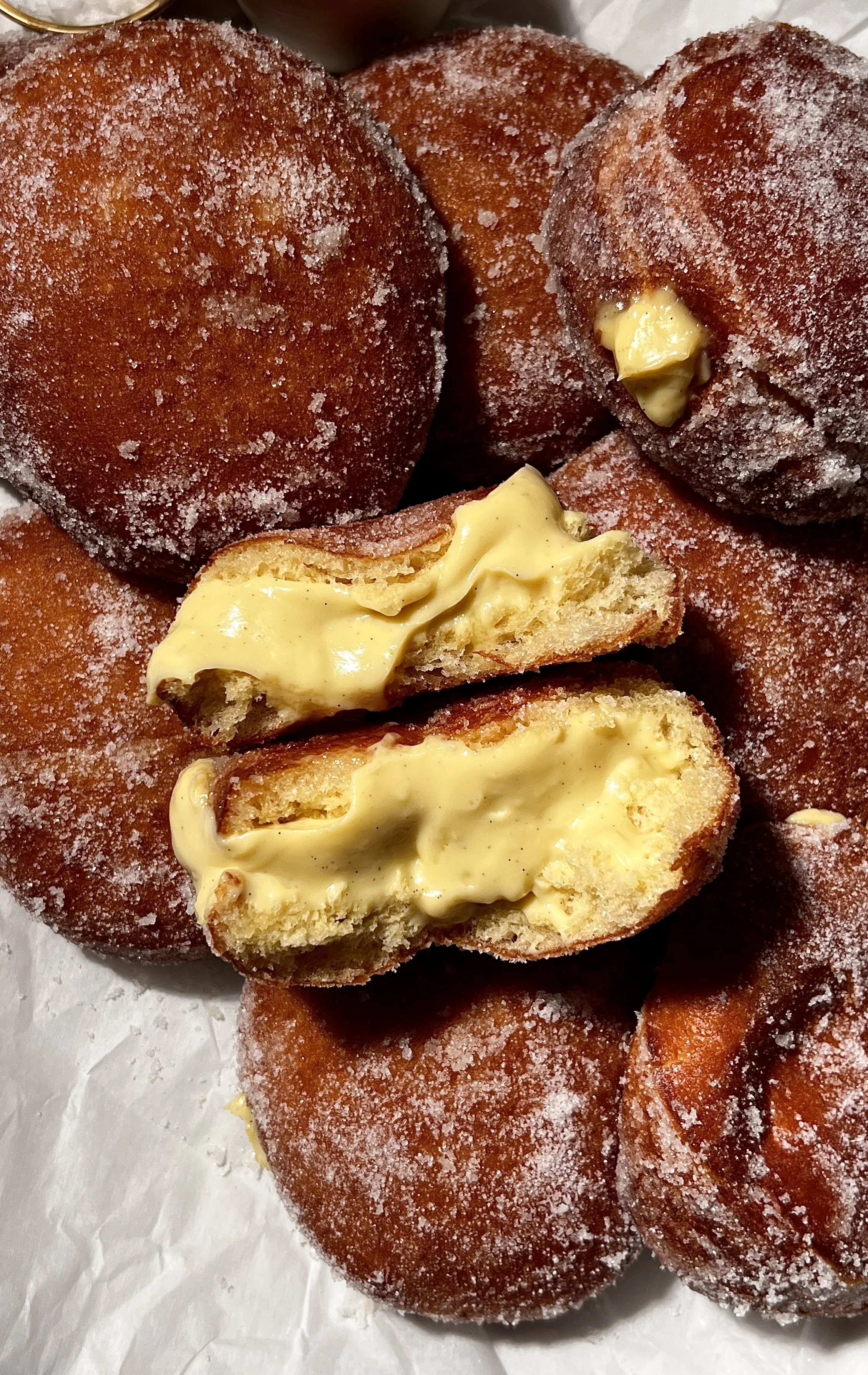 Close-up of vanilla bean coconut cream bomboloni showing the fluffy interior and rich coconut cream filling.