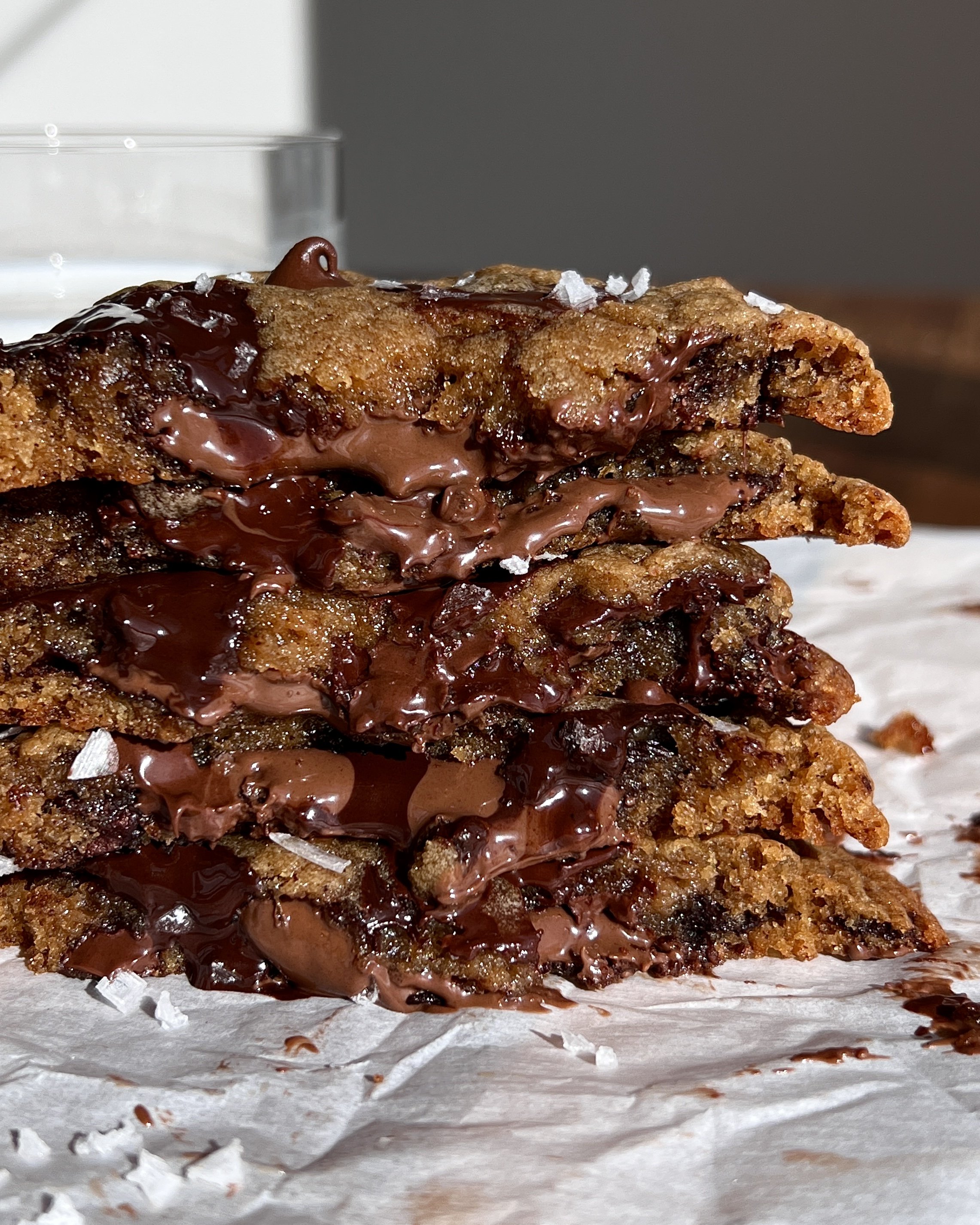 Warm Nutella stuffed banana bread chocolate chip cookies sprinkled with flaky sea salt served with a glass of milk.