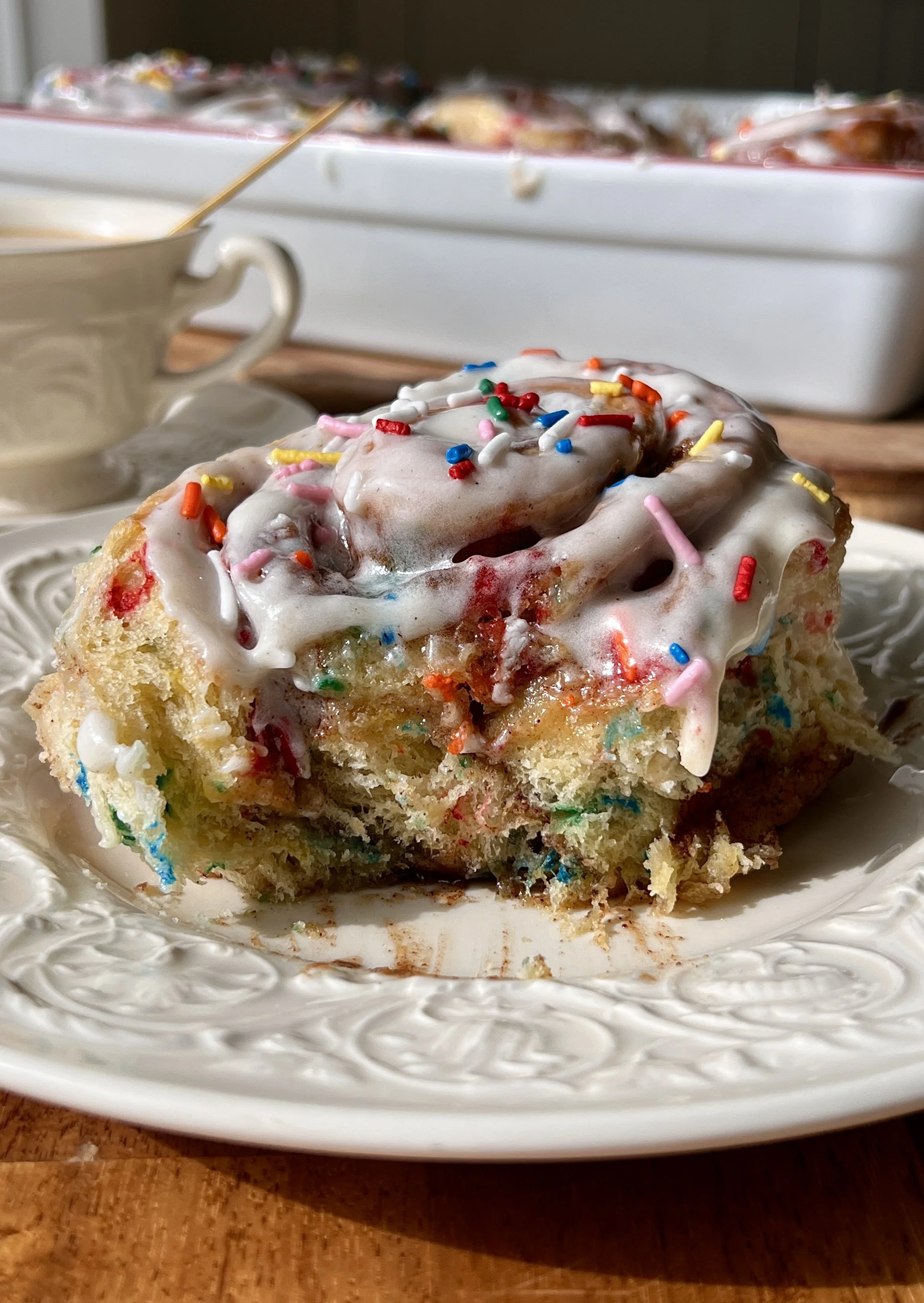 Close-up of a pillowy soft funfetti cinnamon roll with a gooey brown sugar cinnamon filling, cake batter extract, and rainbow sprinkles throughout.