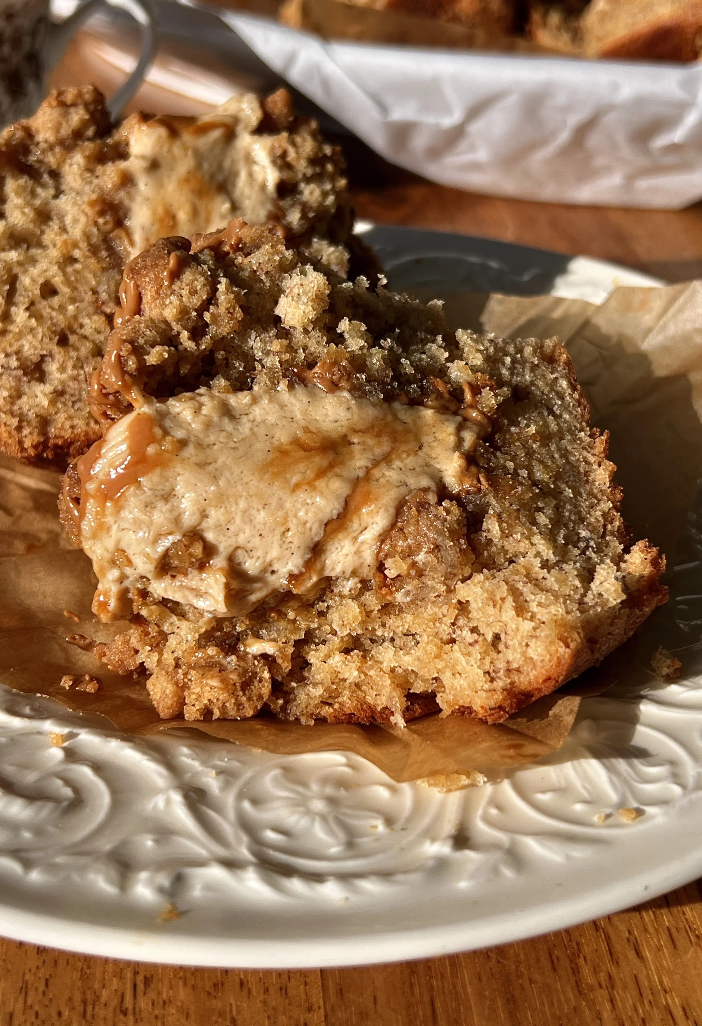 Close-up of a bakery-style banana Biscoff muffin showing the soft fluffy tender banana crumb with a rich Biscoff cream cheese filling and Biscoff cookie butter inside and a golden Biscoff streusel topping.