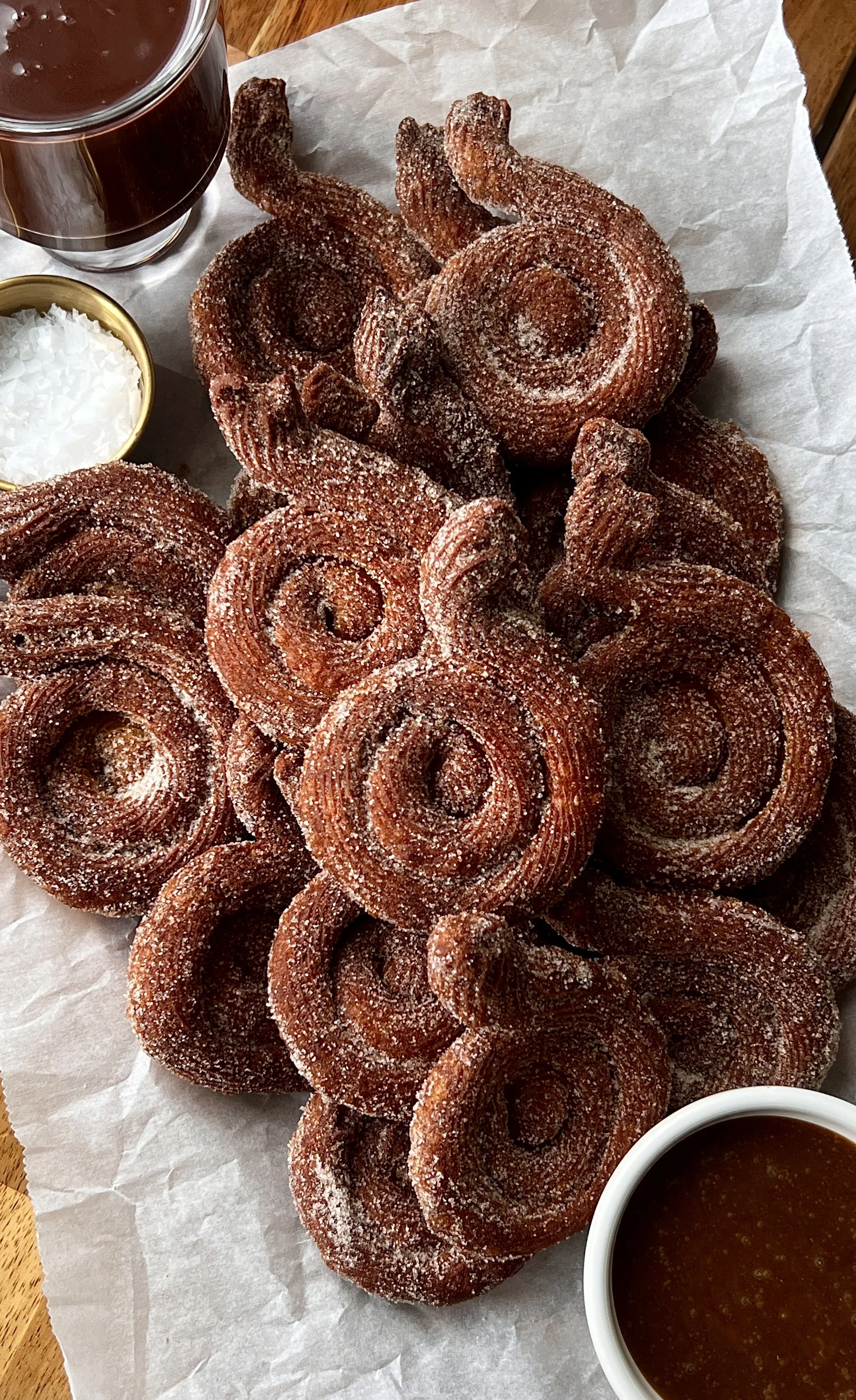 Close-up of pumpkin-shaped Brown Butter Pumpkin Churros coated in cinnamon sugar and served with salted chocolate and caramel sauce