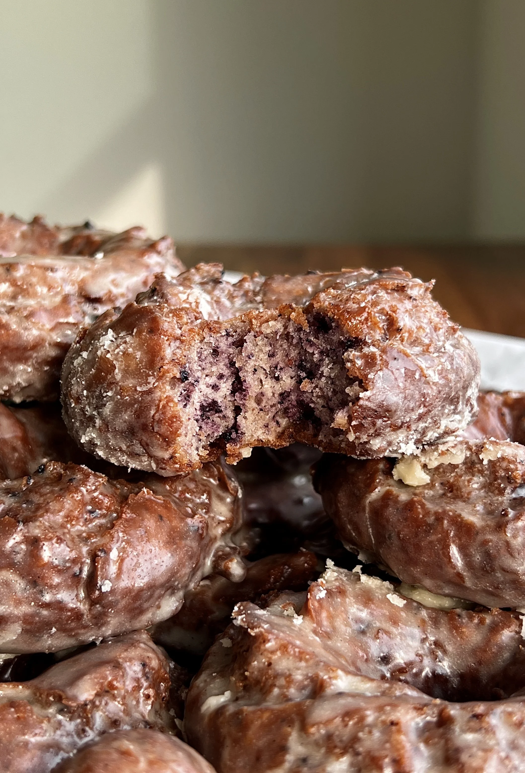 Close-up of blueberry cake donuts with tender crumb and vanilla glaze melting into the cracks.