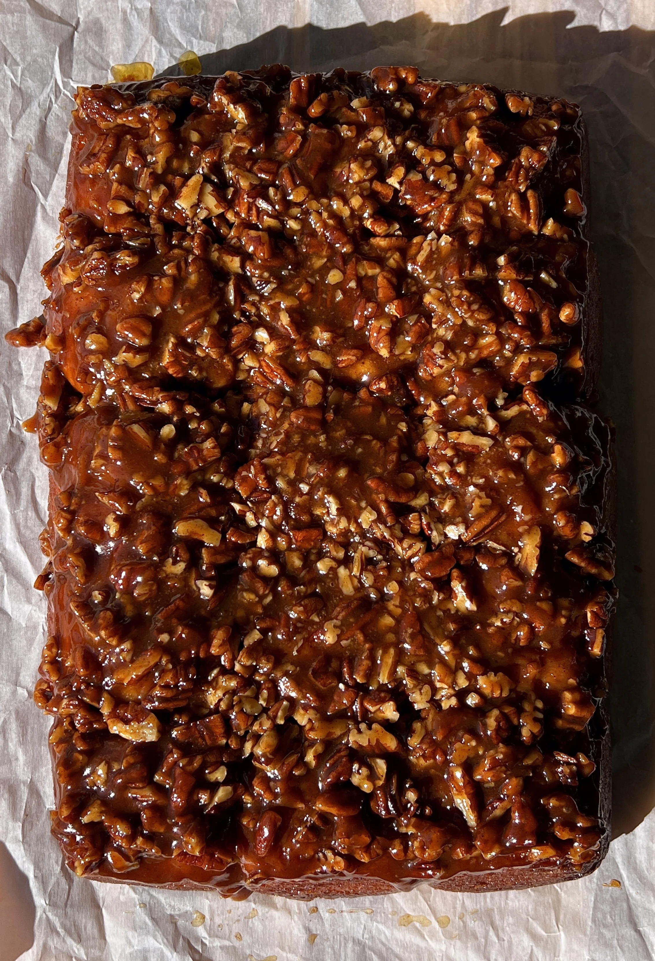 Close-up of a sweet potato sticky roll showing the pillowy soft fluffy and tender spiced sweet potato interior with a gooey caramelized sticky pecan topping.