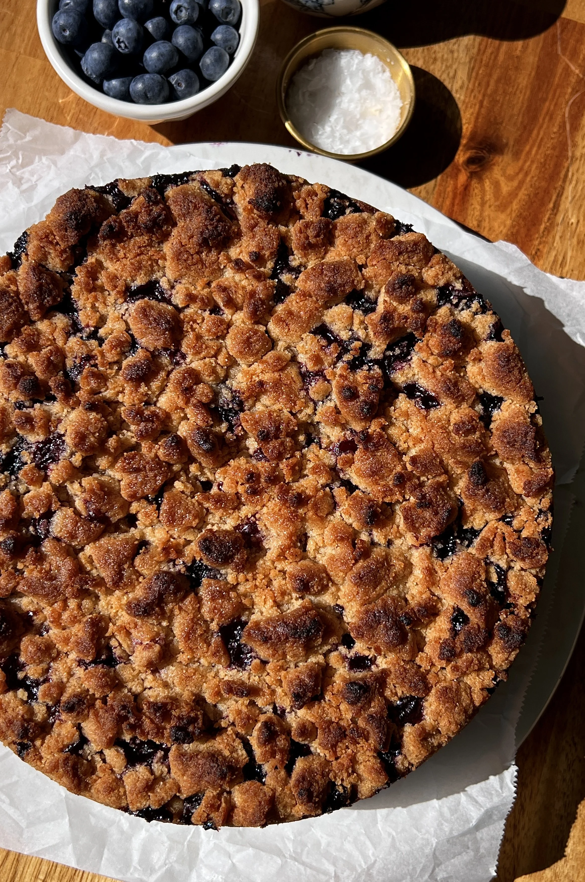 Close-up of a soft and tender brown butter blueberry crumble cake with a bright jammy blueberry layer and golden buttery crumble topping throughout.