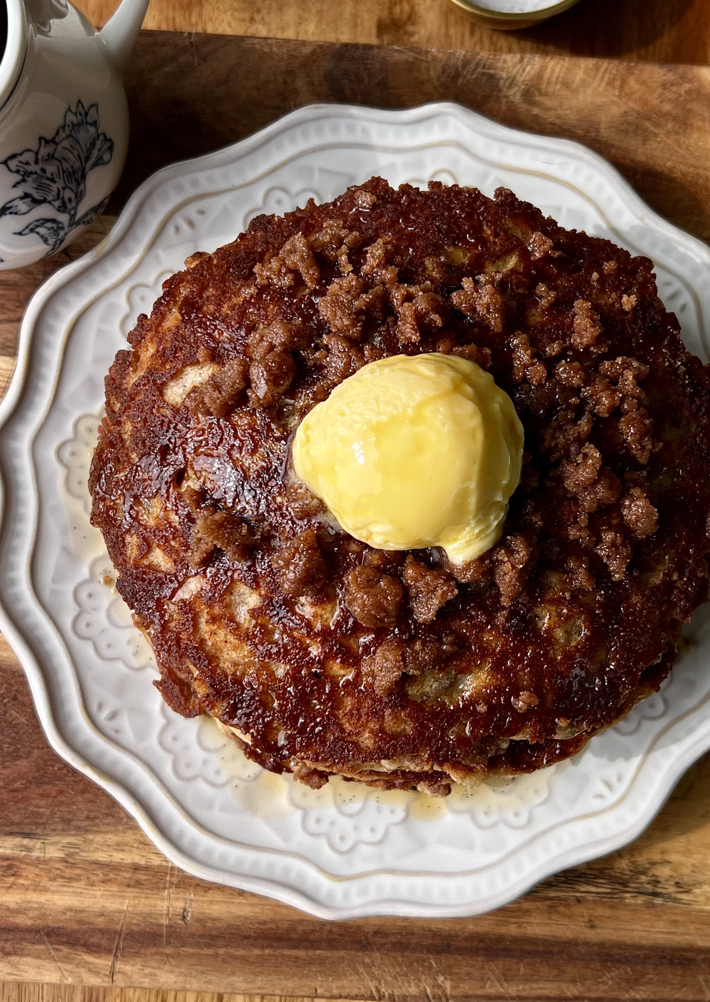Close-up of a fluffy banana coffee cake pancake with a beautifully golden exterior and crisp edges with a warm cinnamon streusel caramelized throughout.