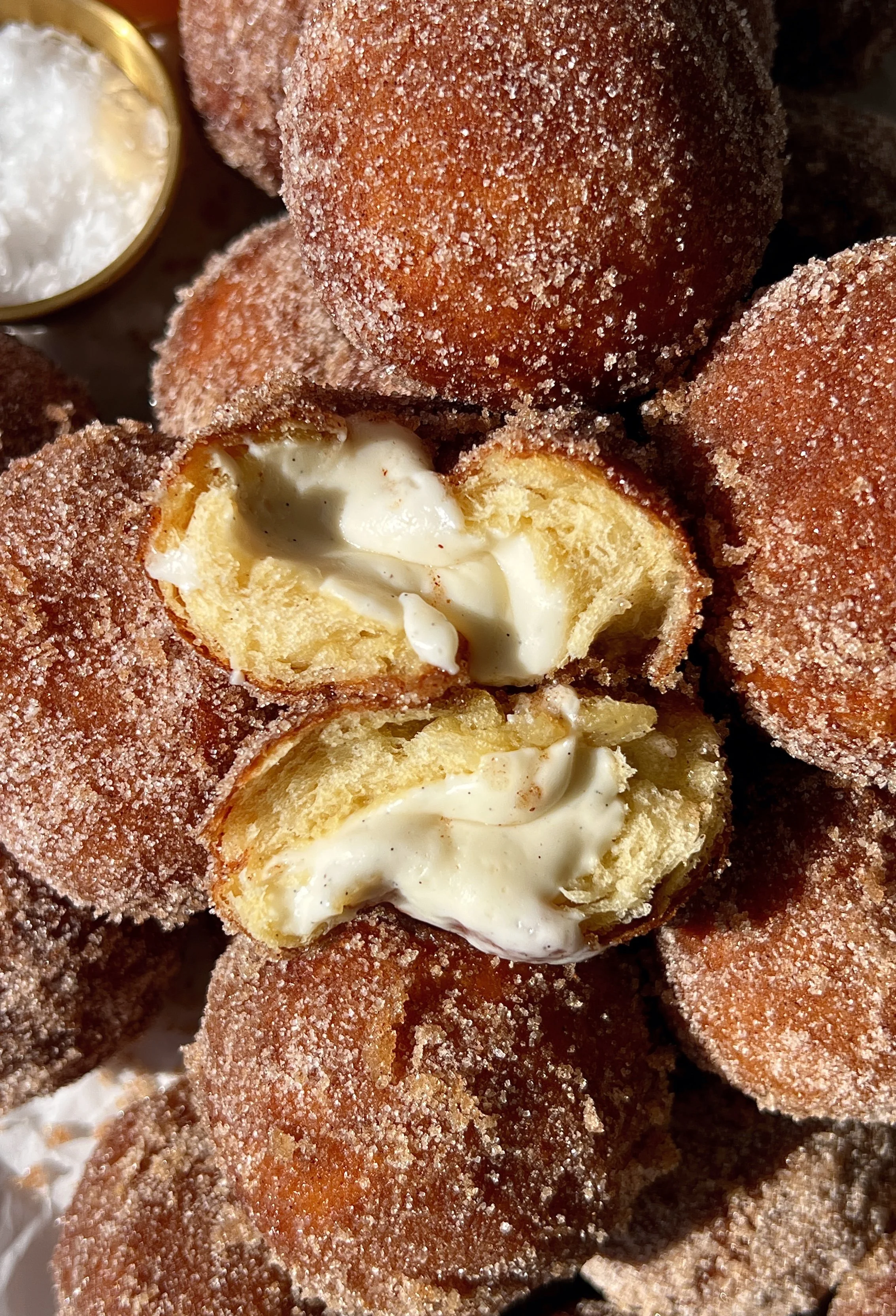 Close-up of an apple cider cinnabon delight showing the soft pillowy golden exterior rolled in cinnamon sugar with a sweet tangy cream cheese filling inside.