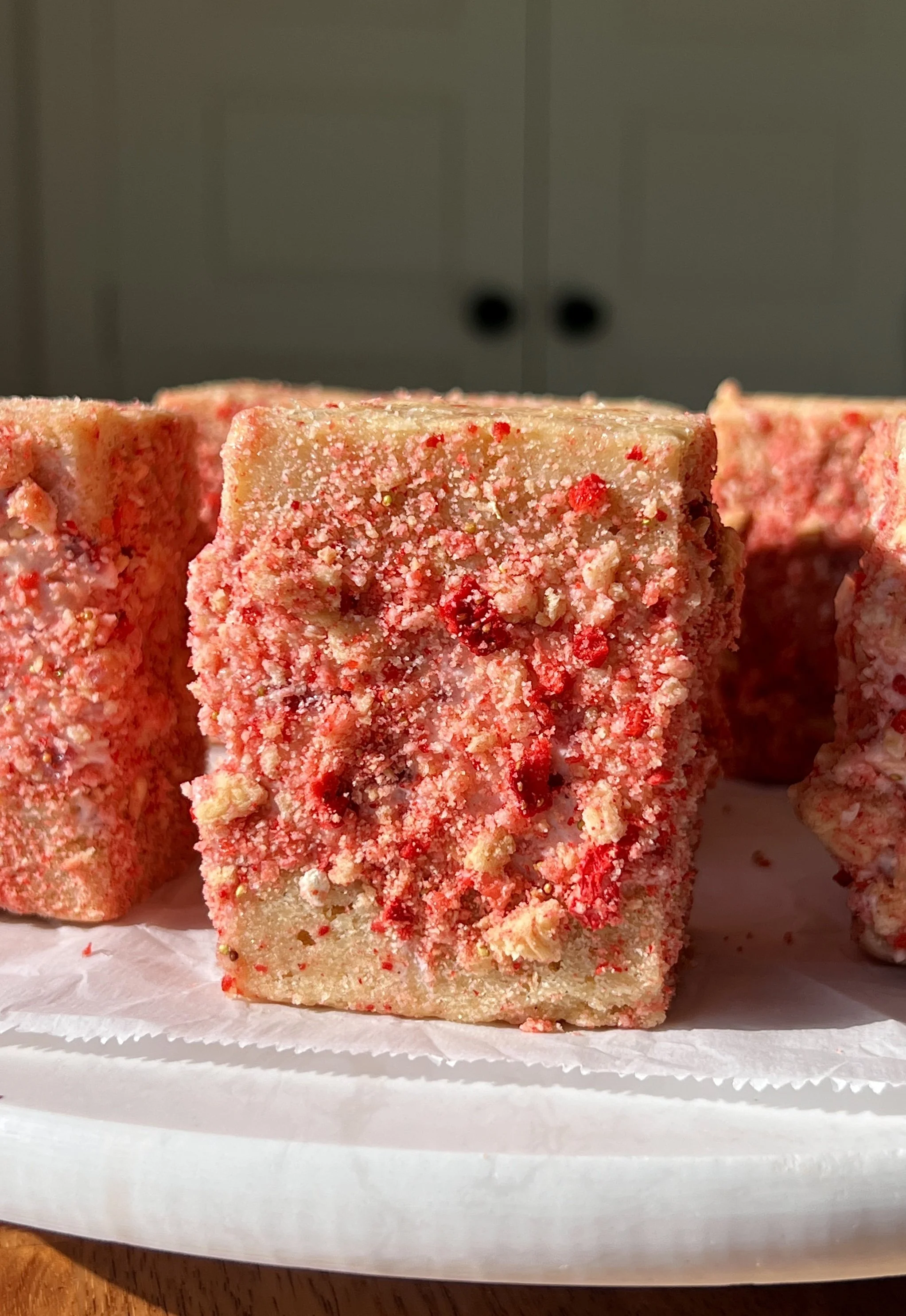 Close-up of a strawberry shortcake shortbread ice cream sandwich showing the soft buttery shortbread layers with rich and creamy homemade no-churn strawberry ice cream coated in a strawberry shortcake crunch coating throughout.