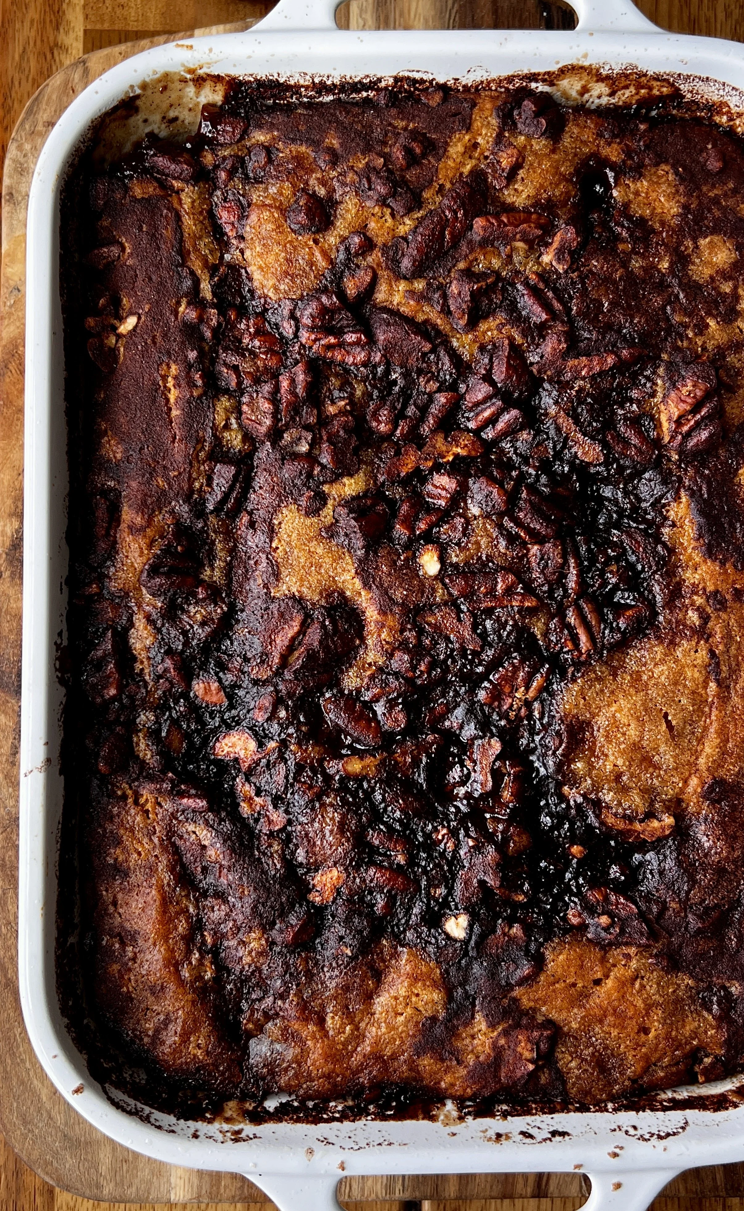 Golden brown butter sweet potato pecan cobbler with a gooey base and crisp top, topped with vanilla ice cream and a sprinkle of flaky sea salt, served warm in a baking dish with pecans scattered around.