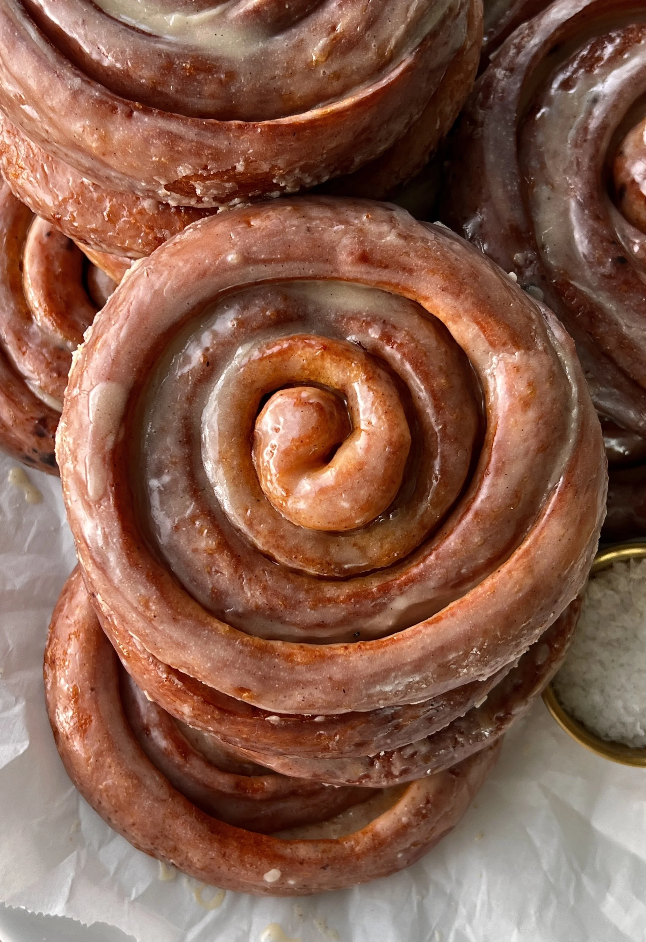 Close-up of a pumpkin spice honey bun showing the soft pillowy pumpkin dough with gooey swirls of honey butter and pumpkin spice brown sugar filling and a honey glaze sinking into every crack.