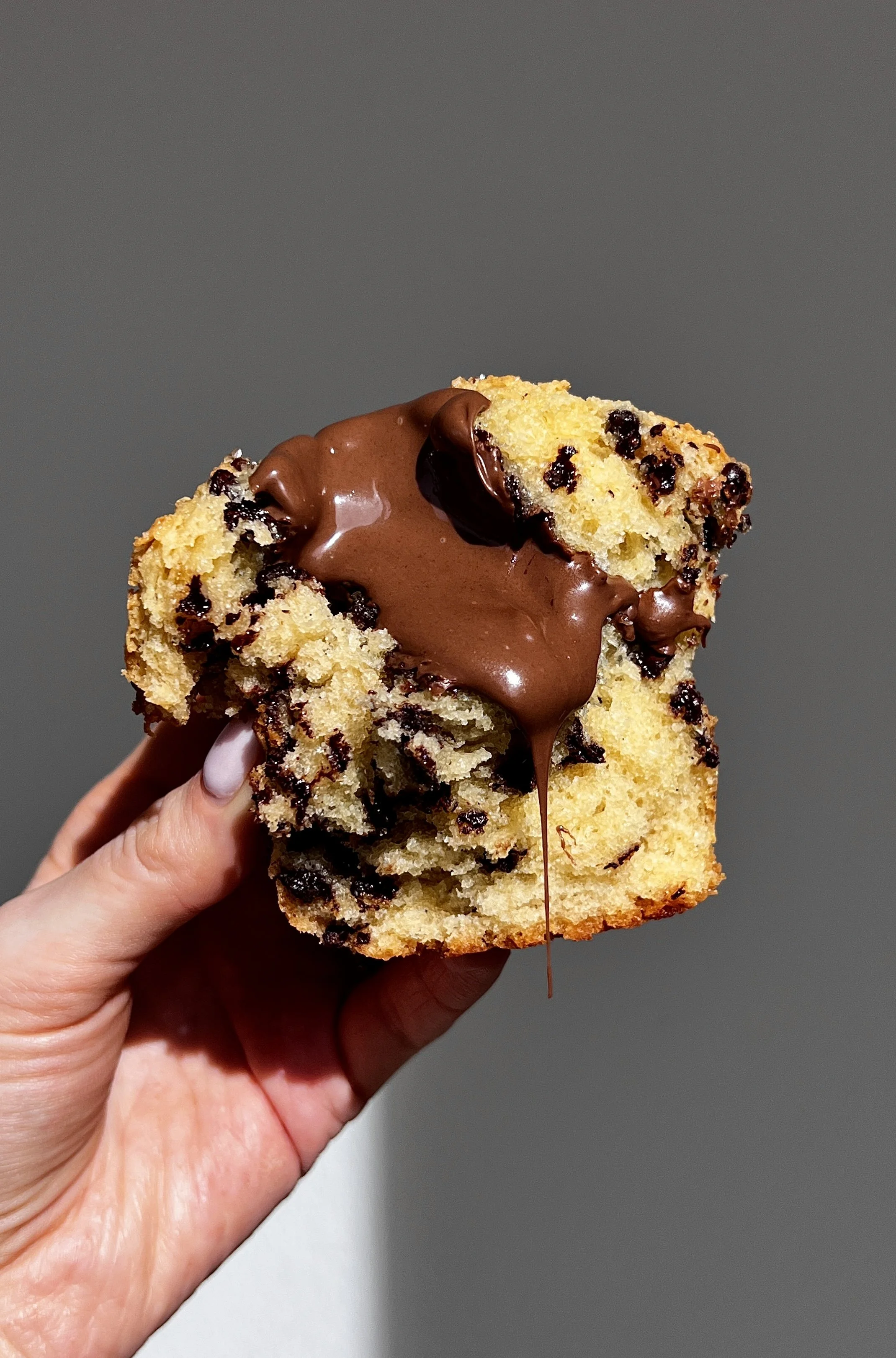 Close-up of a Nutella stuffed chocolate chip muffin showing melty chocolate chips and gooey center.
