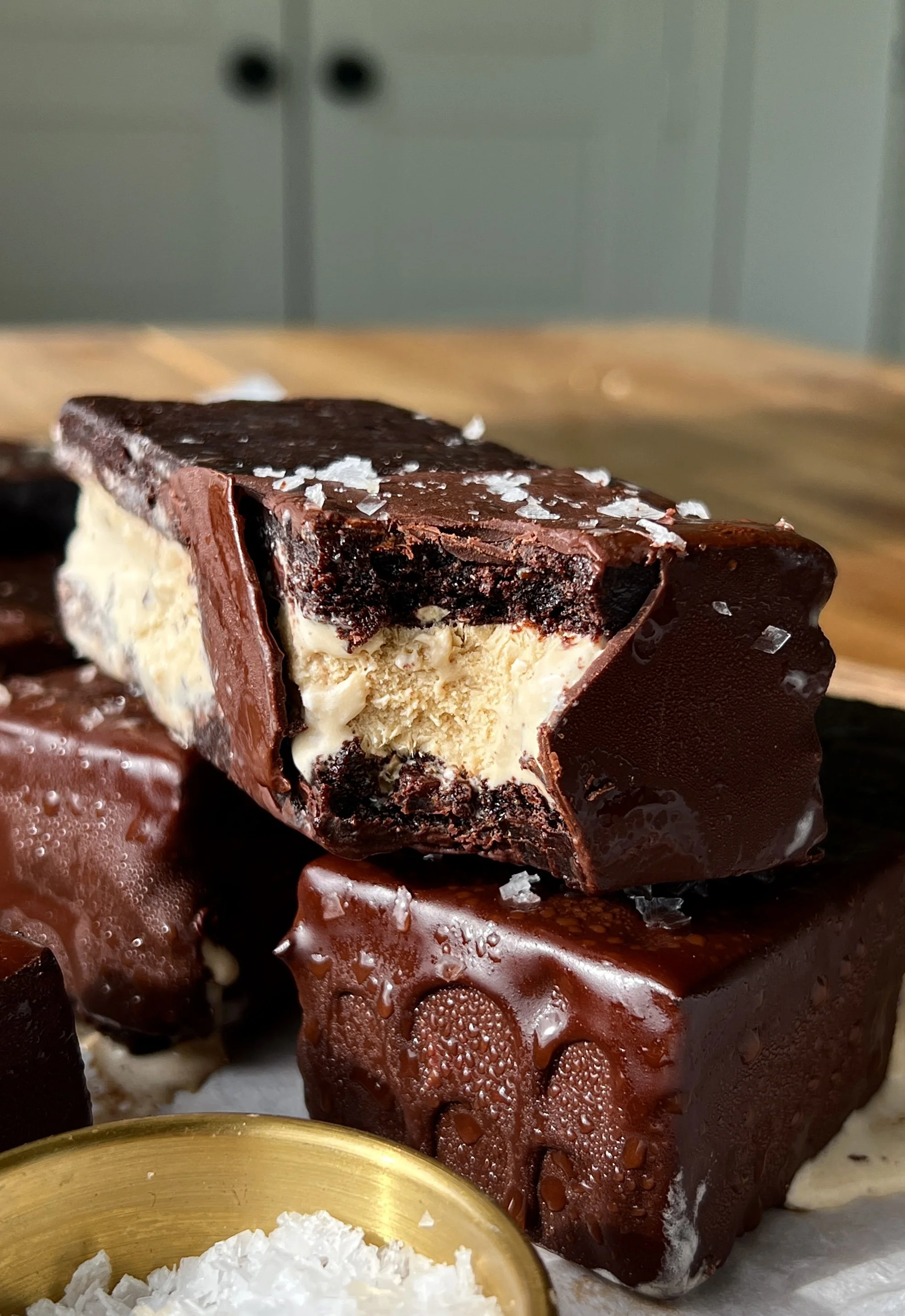 Brownie ice cream sandwich with a bite taken out showing the fudgy brownie layers with rich and creamy coffee chip ice cream loaded with chocolate chunks inside dipped in chocolate.