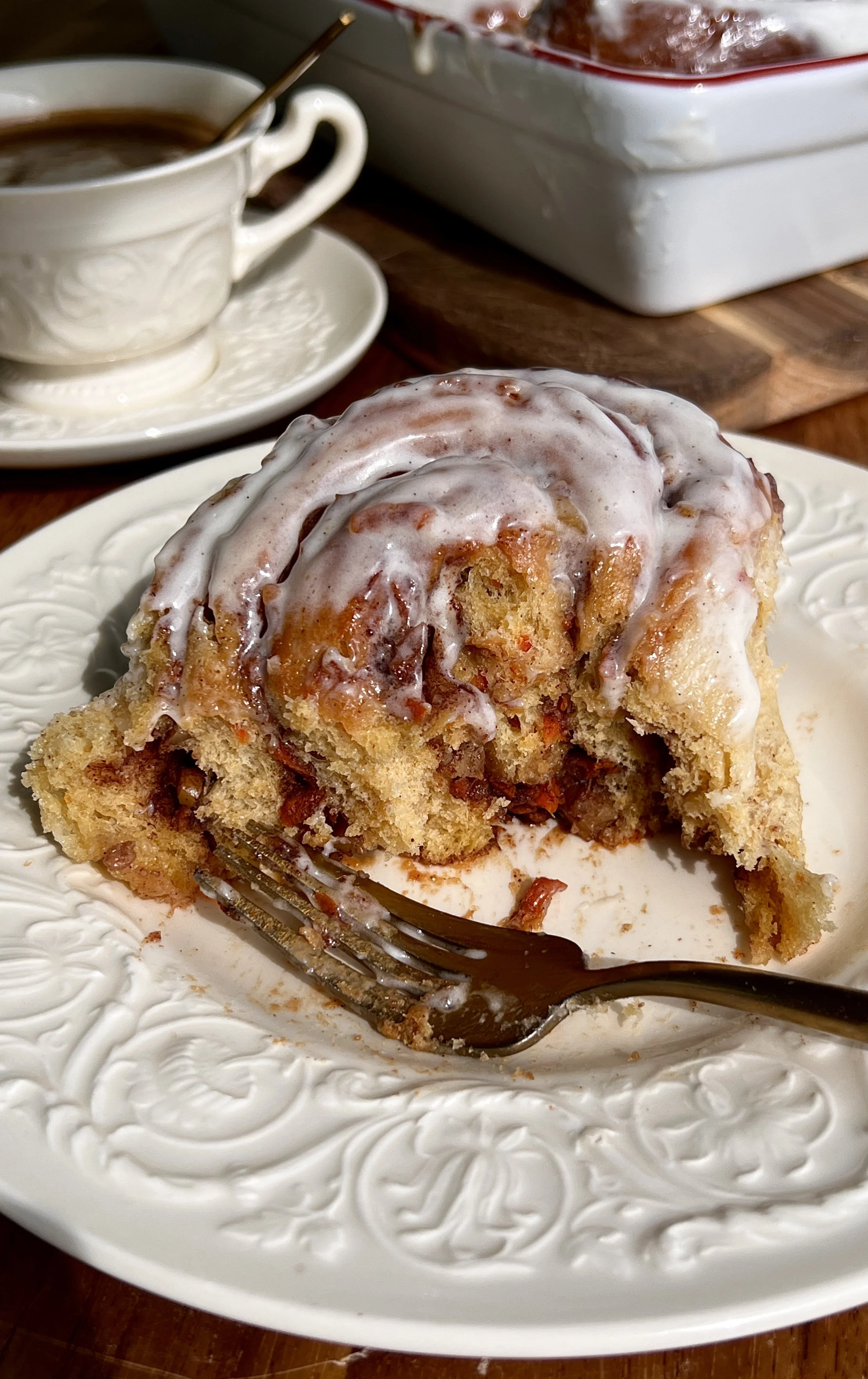 Close-up of carrot cake cinnamon rolls with gooey cinnamon sugar swirls, grated carrots, and chopped walnuts.
