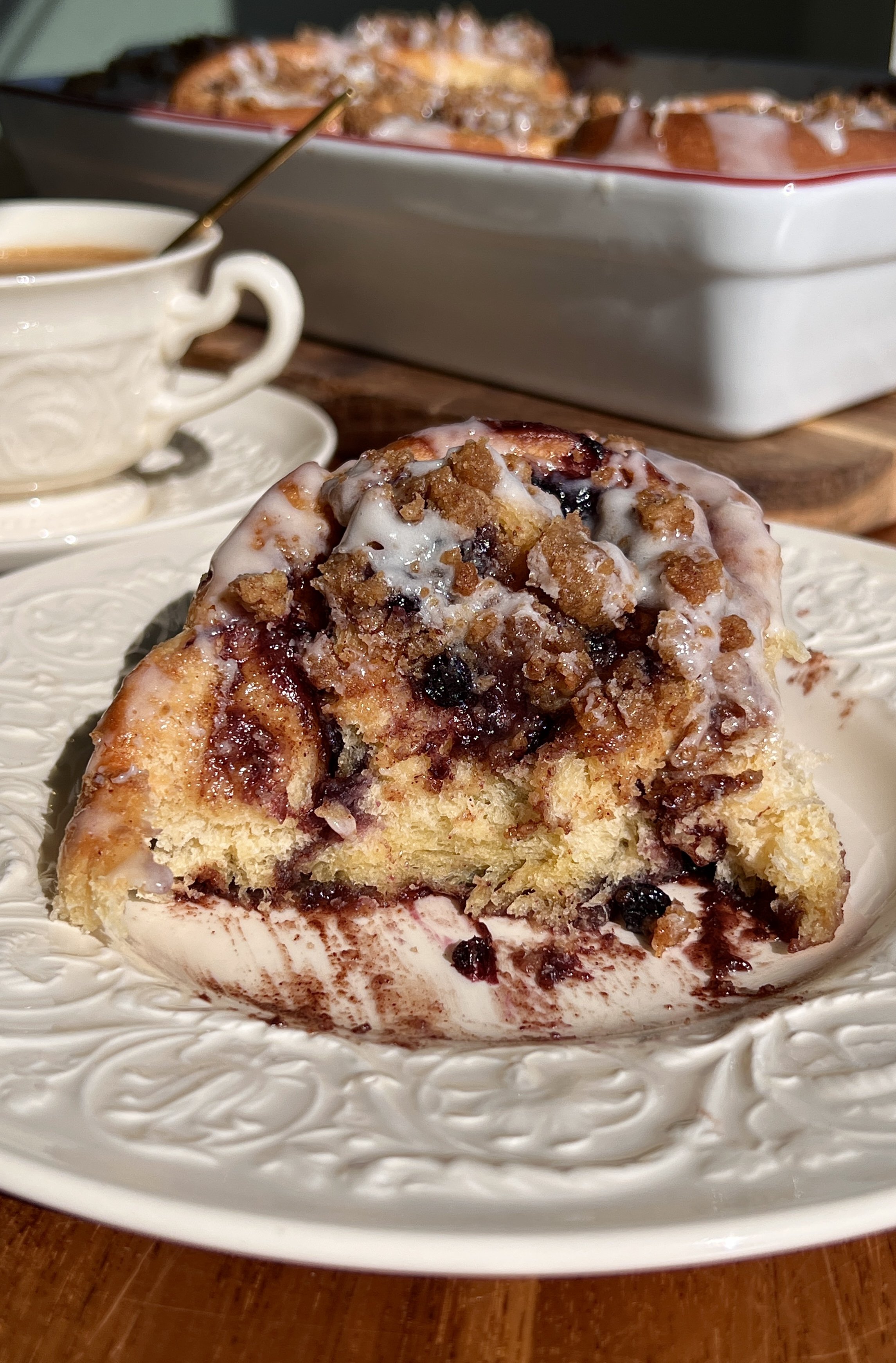 Soft blueberry cinnamon roll being pulled apart with gooey filling and blueberry compote inside.