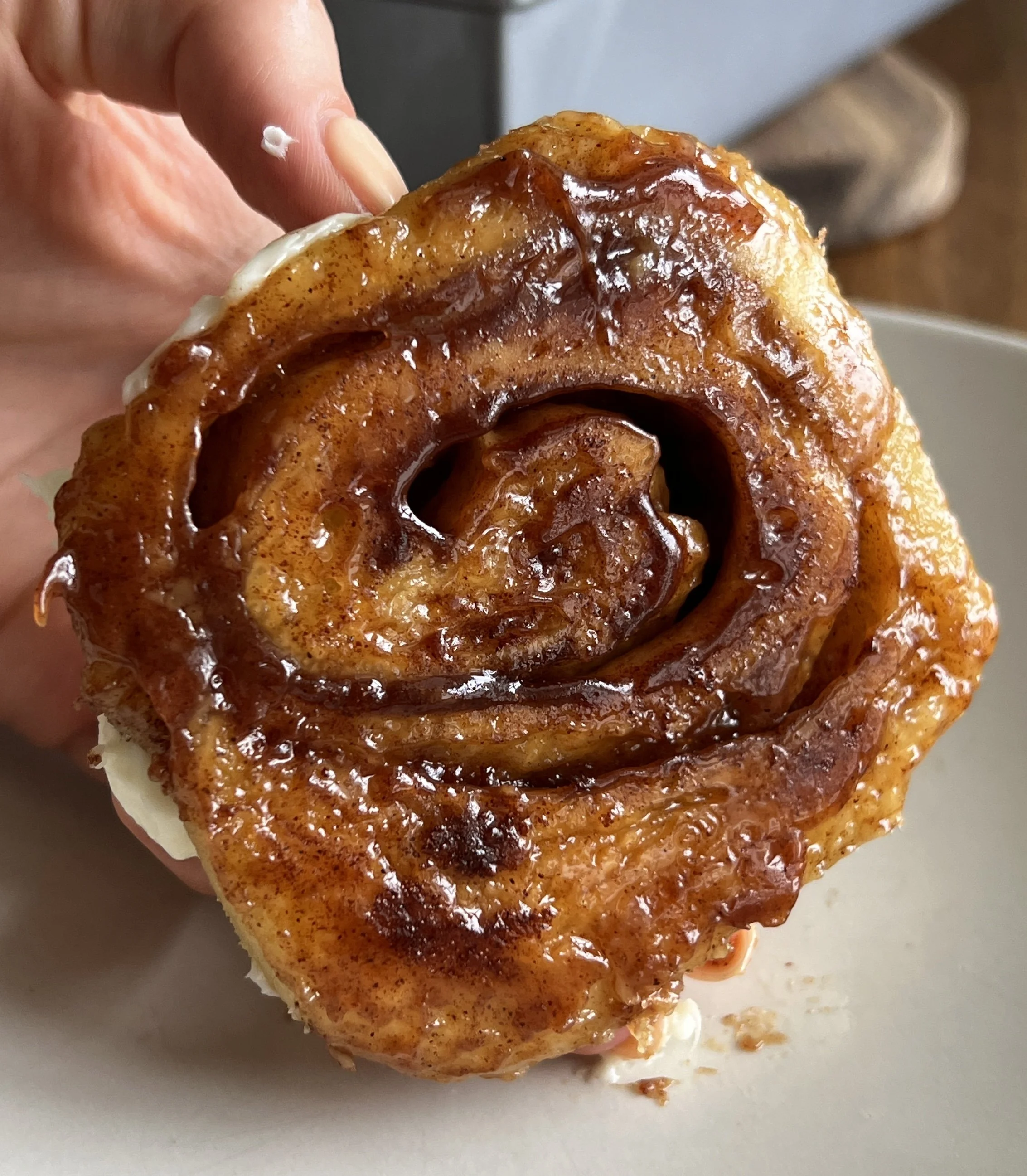 Close-up of Sourdough Cinnamon Rolls with a golden exterior, topped with cream cheese icing. The fluffy rolls are swirled with cinnamon sugar filling, promising a decadent treat. The icing adds a creamy finishing touch to these homemade delights.