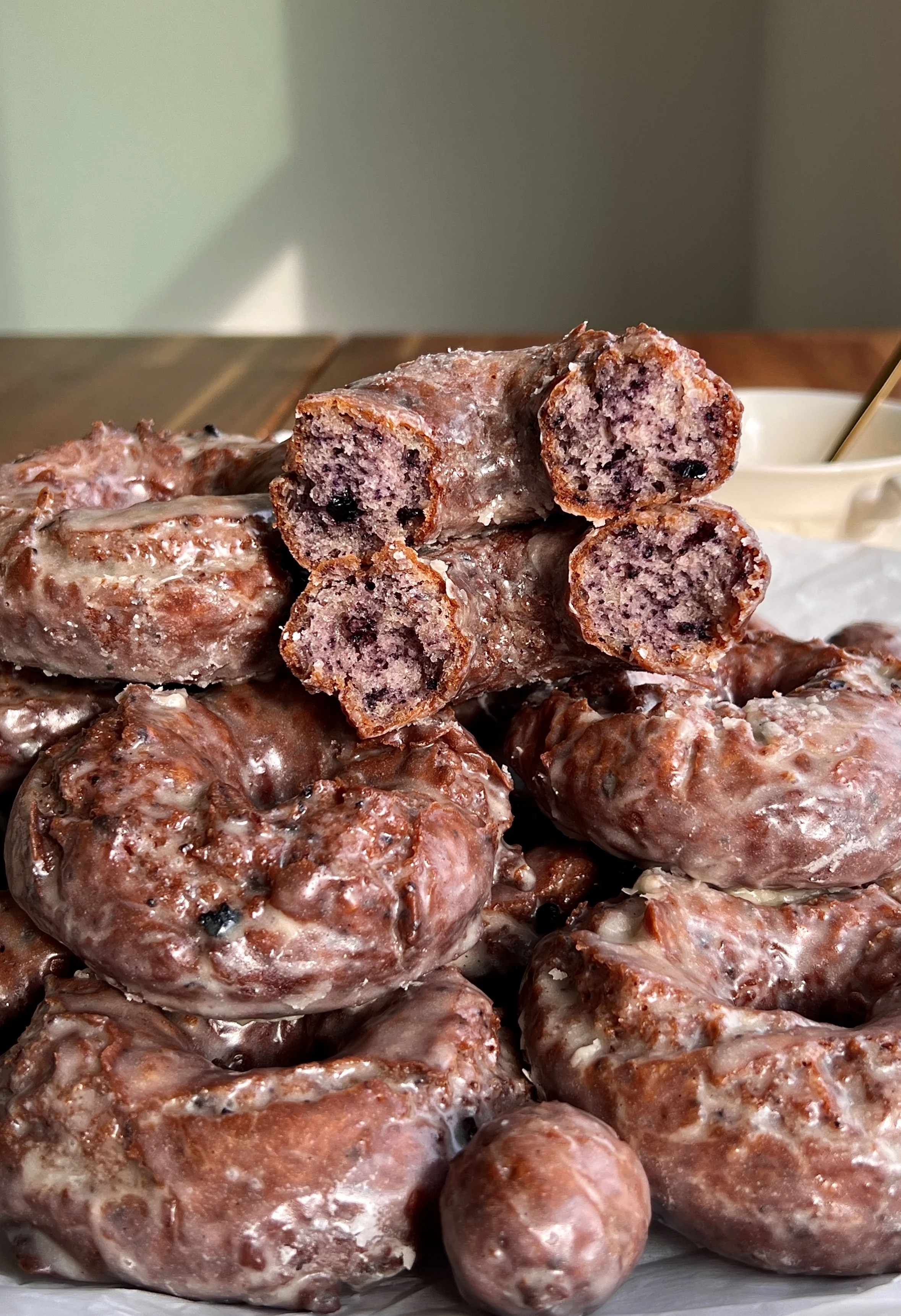 Stack of old-fashioned blueberry cake donuts coated in vanilla bean glaze.