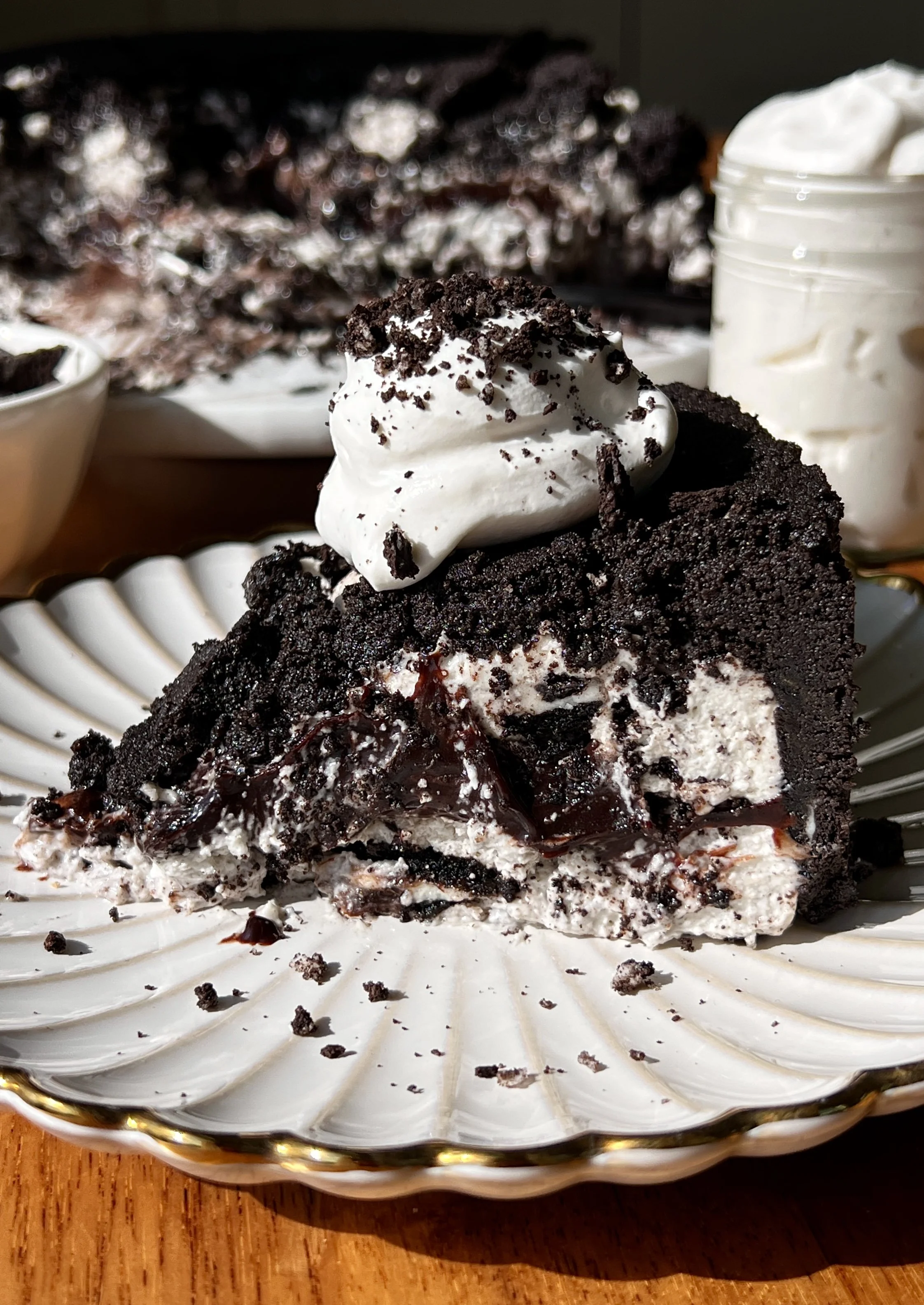 Upside down cookies and cream no-bake cheesecake with a buttery crunchy Oreo cookie crust on top inverted to serve and finished with a dollop of whipped cream and crushed Oreo cookies as the ultimate fun and impressive no-bake dessert.