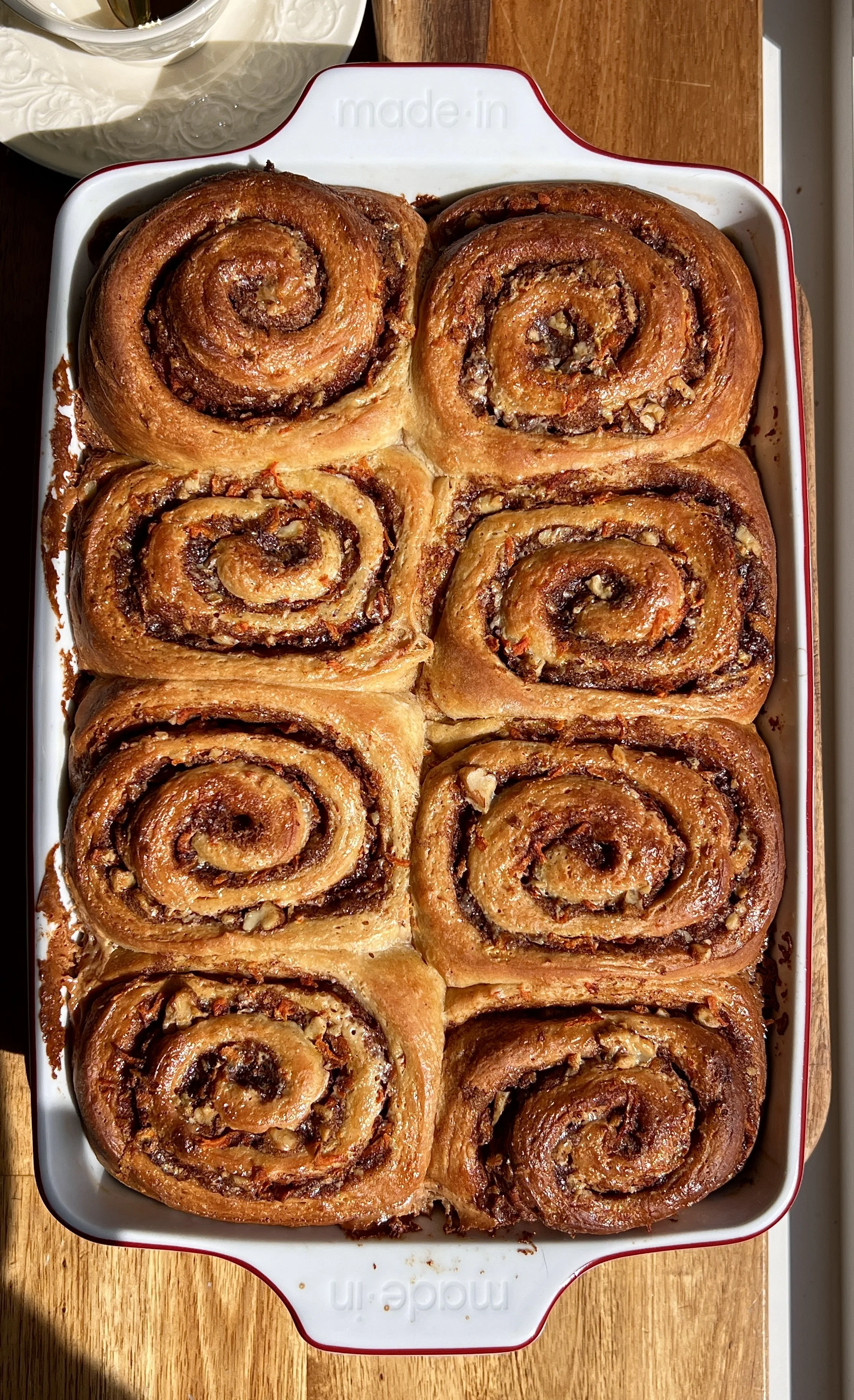 Close-up of carrot cake cinnamon rolls with gooey cinnamon sugar swirls, grated carrots, and chopped walnuts.