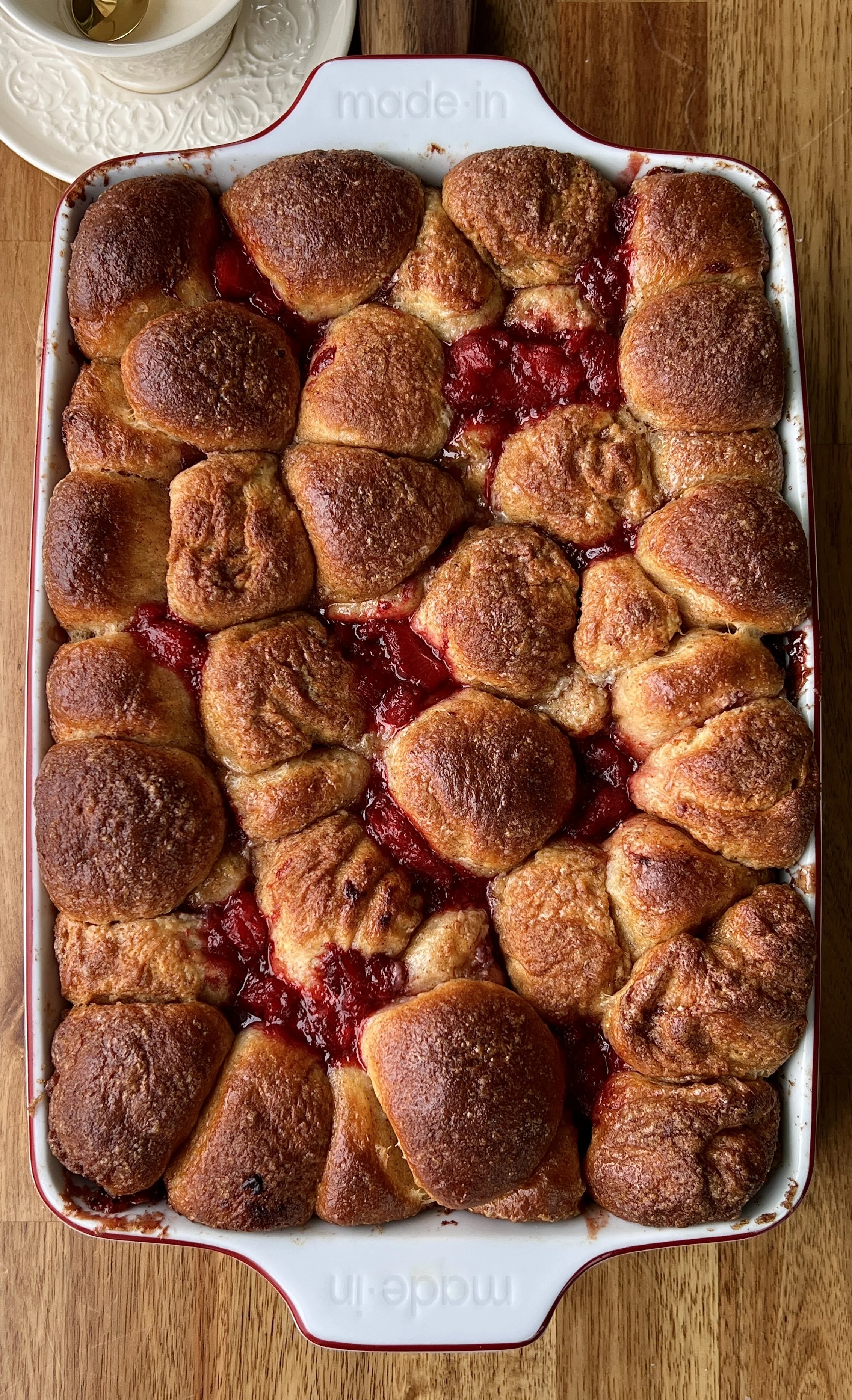 Close-up of soft and fluffy strawberry cinnamon roll bites rolled in brown sugar cinnamon with a glossy homemade strawberry compote and brown sugar syrup throughout.