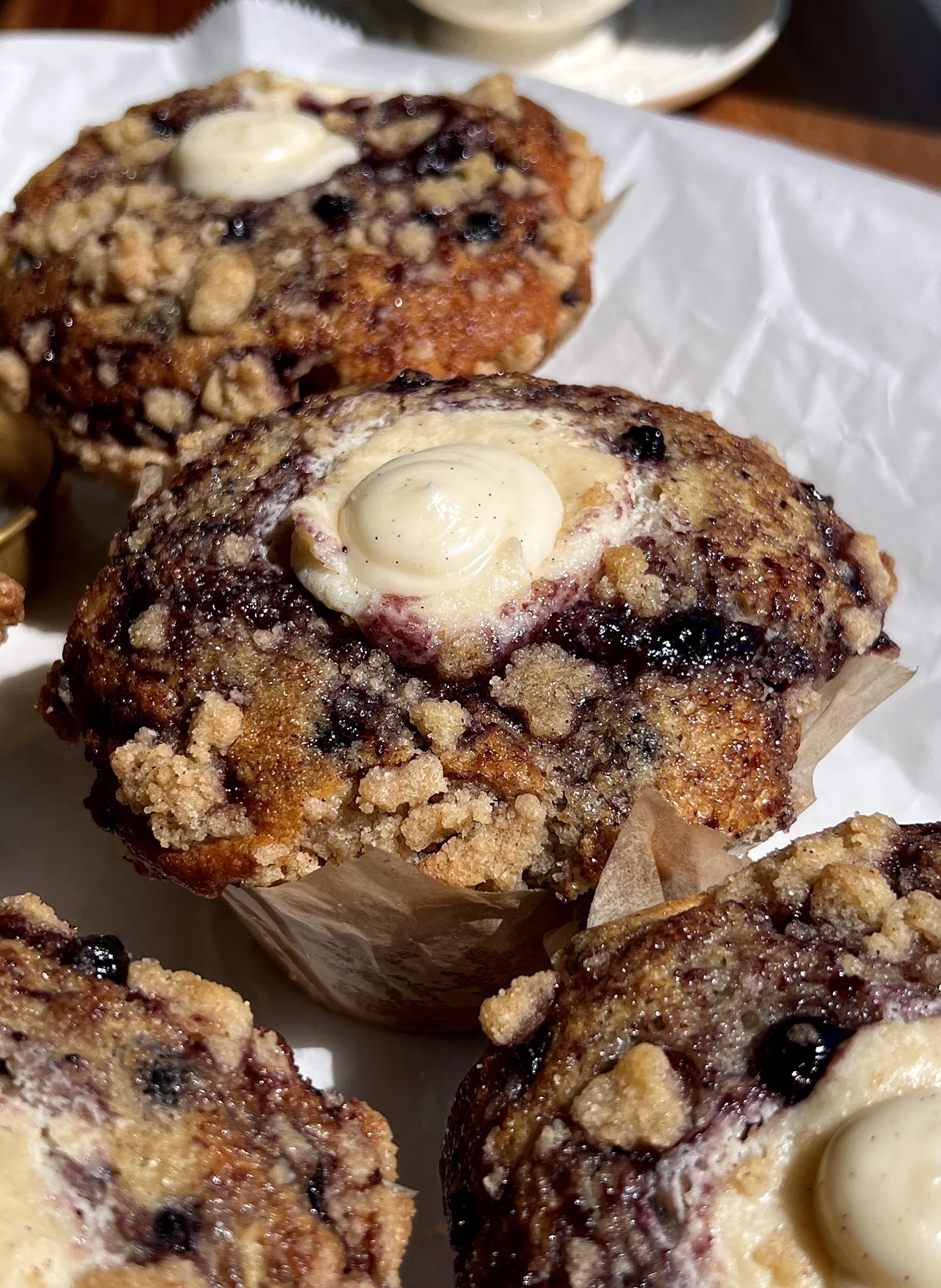 Close-up of blueberry cream cheese muffins with soft crumb, juicy blueberries, and buttery crumb topping.