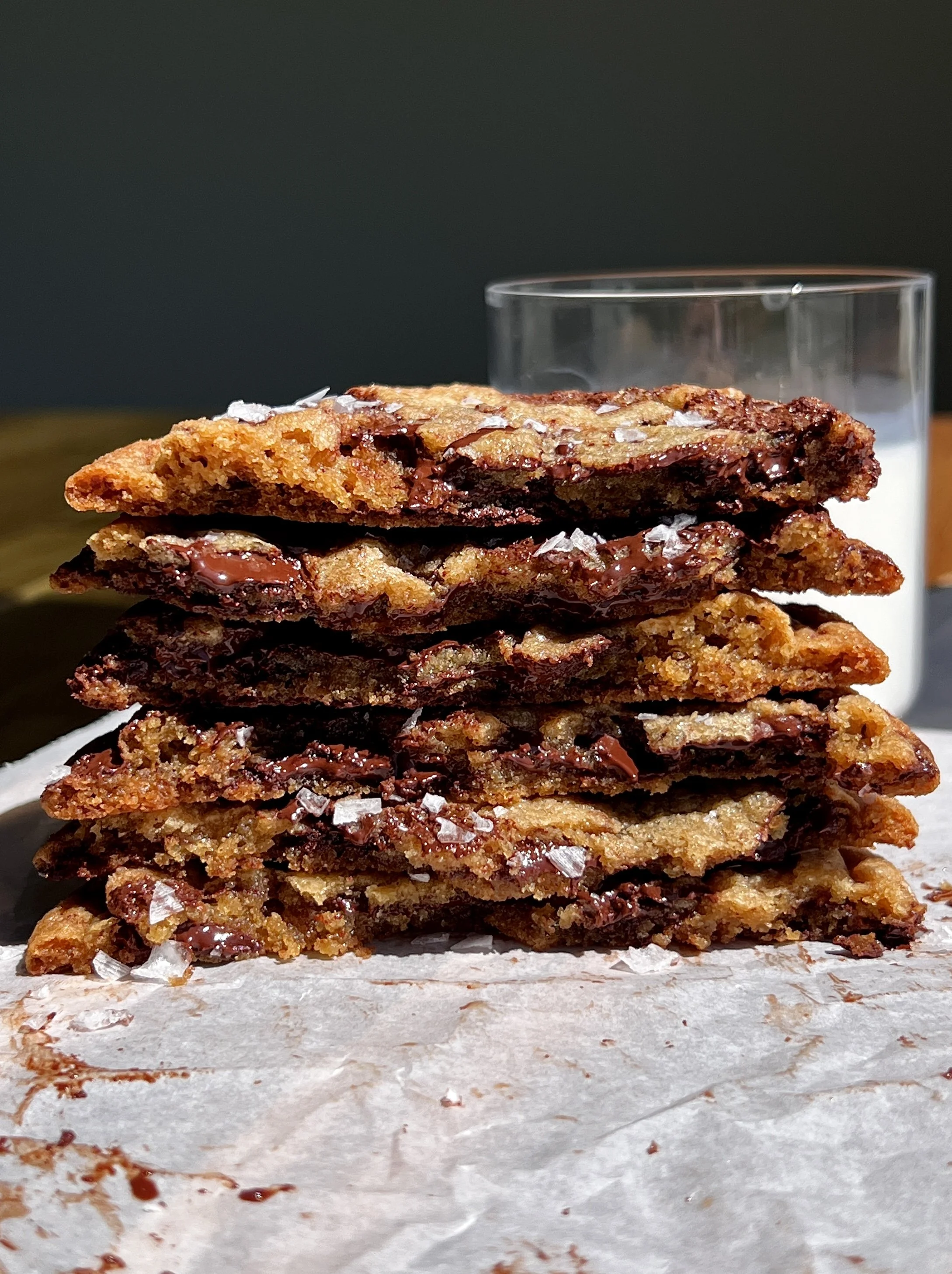 Warm brown butter chocolate chip cookies served with flaky sea salt and a glass of milk.