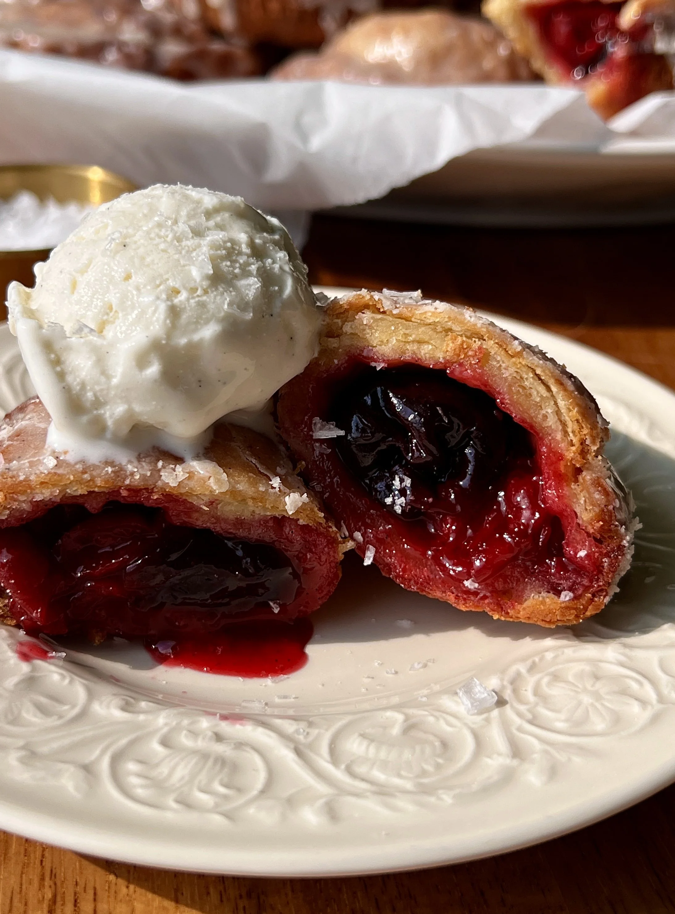 Close-up of a golden fried cherry hand pie with a flaky buttery crust and sweet and tart homemade cherry pie filling bursting throughout.