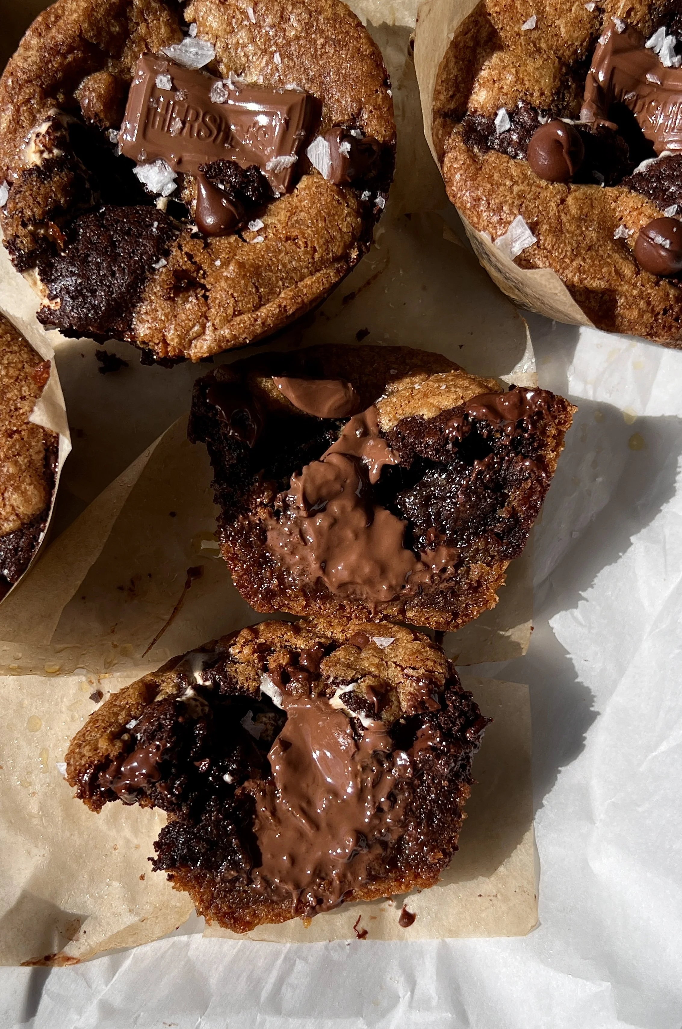 Close-up of a fudgy brown butter s'mores brookie cup with a golden crisp exterior showing the layers of brown butter cookie dough, brownie, graham cracker, marshmallow, and melty milk chocolate throughout.