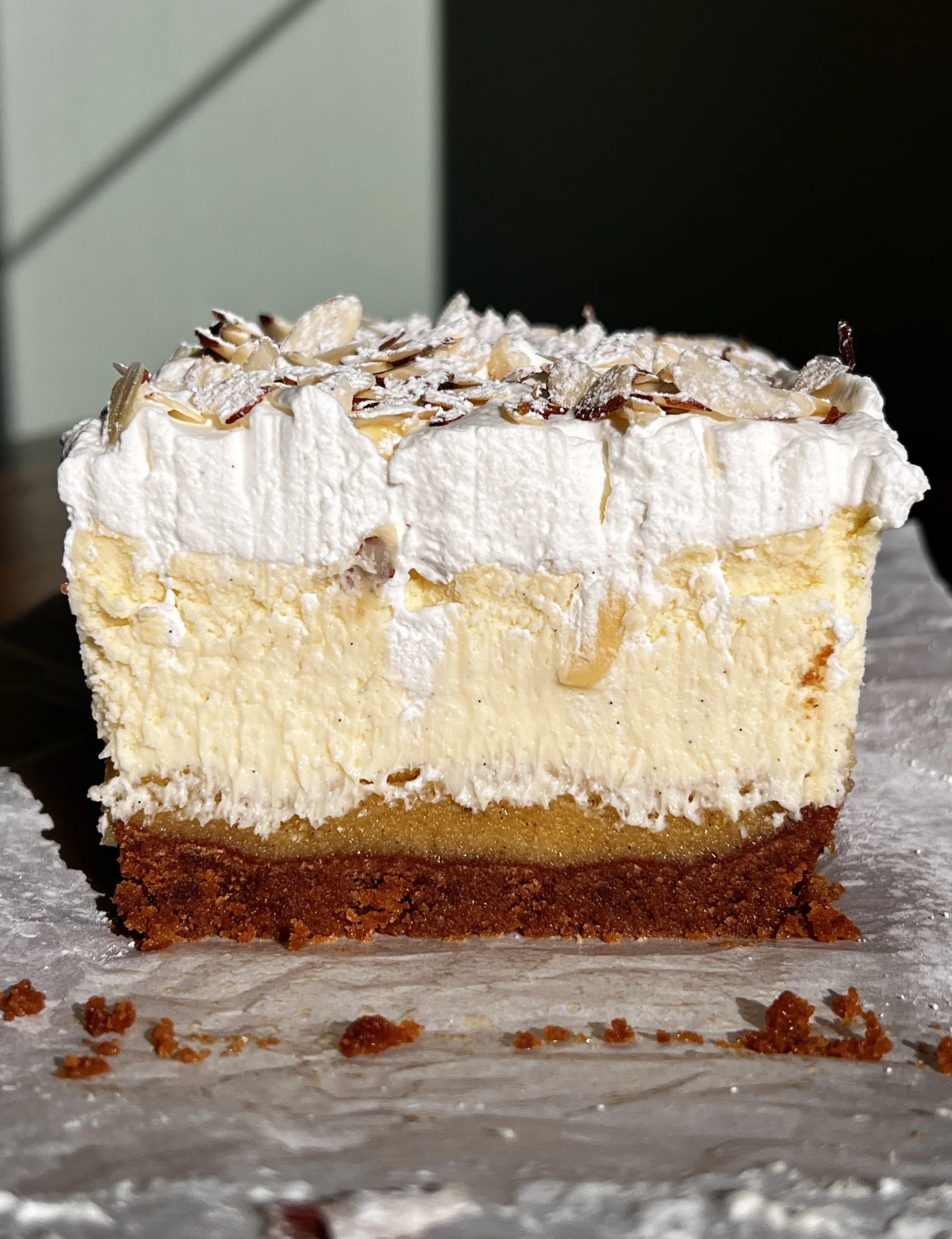 Close-up of an almond frangipane cheesecake bar with soft frangipane layer and tangy vanilla cheesecake.