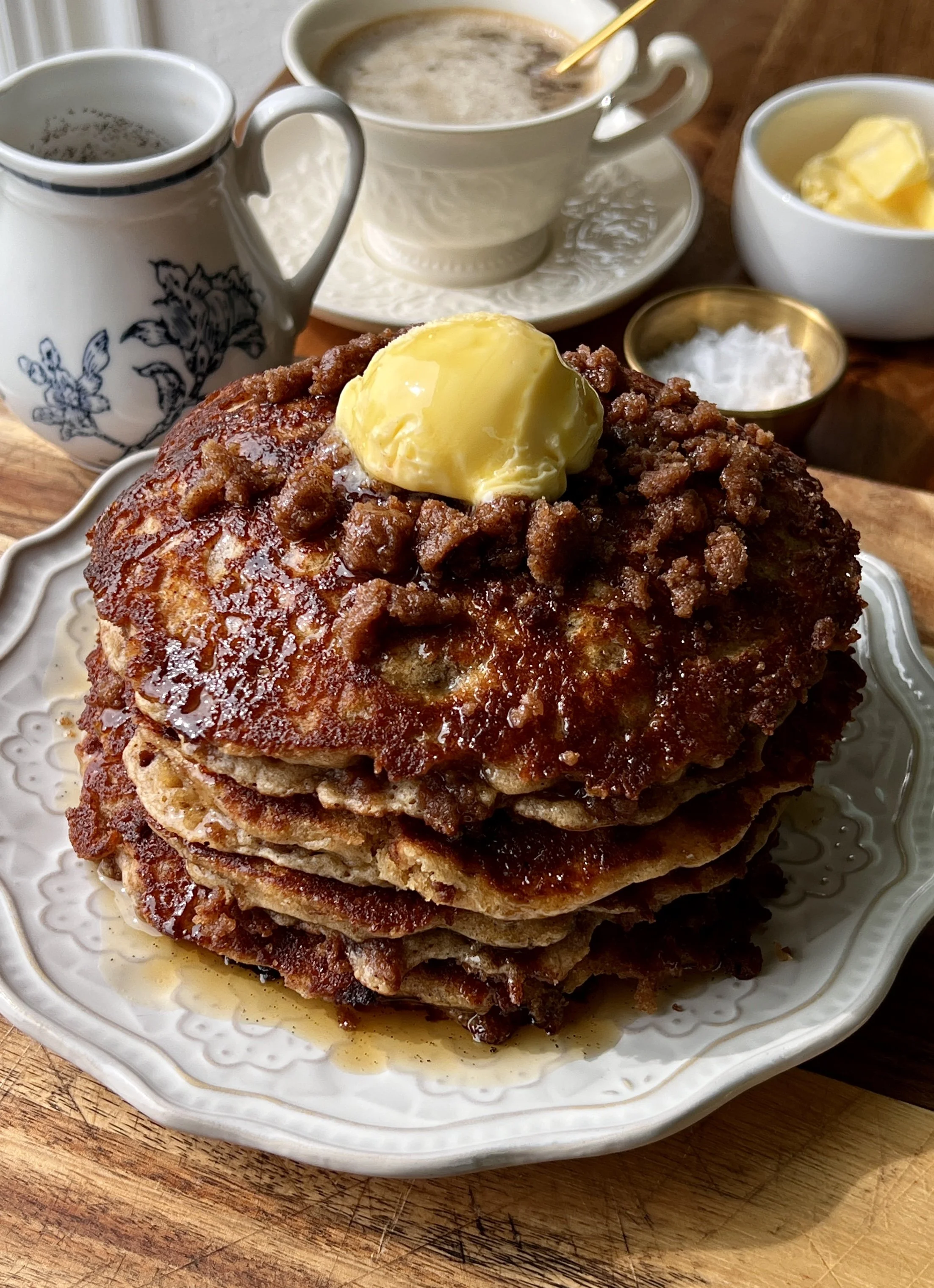 Banana coffee cake pancakes served warm with a pat of butter and a drizzle of warm vanilla bourbon maple syrup with a hot cup of coffee.