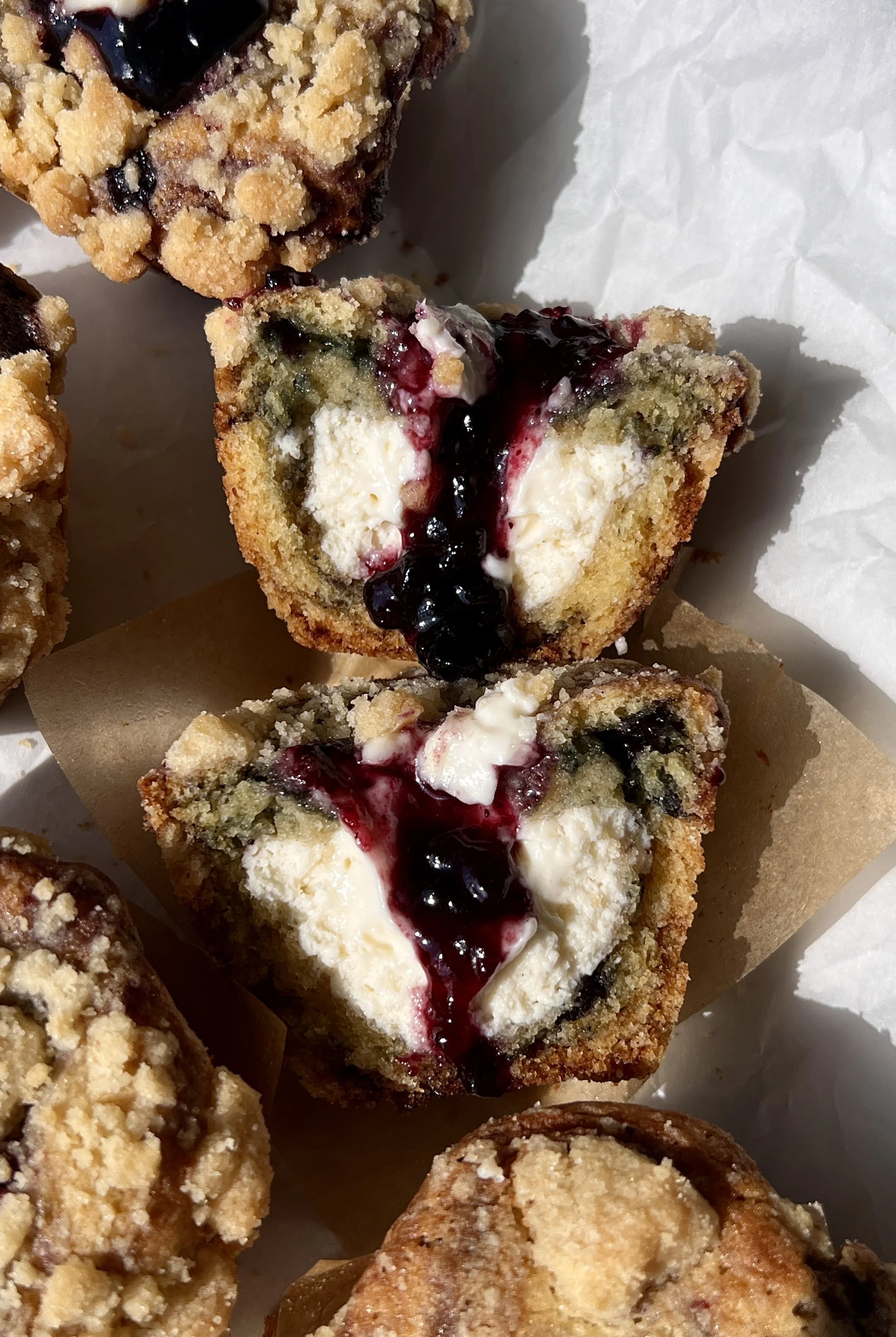 Close-up of a soft and buttery blueberry muffin cheesecake cookie cup with a rich and creamy cheesecake filling and perfectly golden crumble topping throughout.