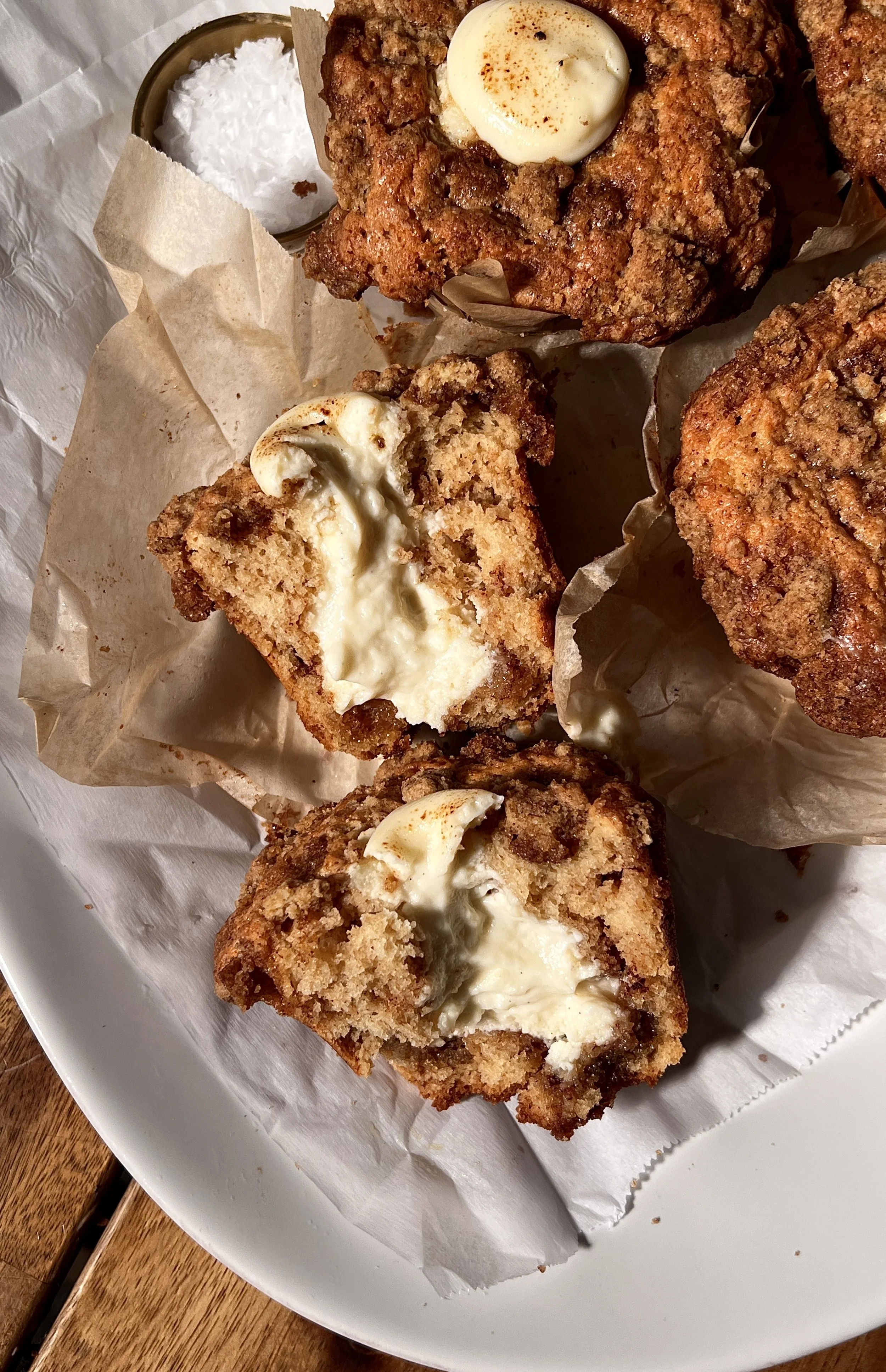 Brown butter cinnamon roll cream cheese muffins with a tender crumb, cinnamon swirl throughout, and a crumb topping, served warm with a cup of coffee.