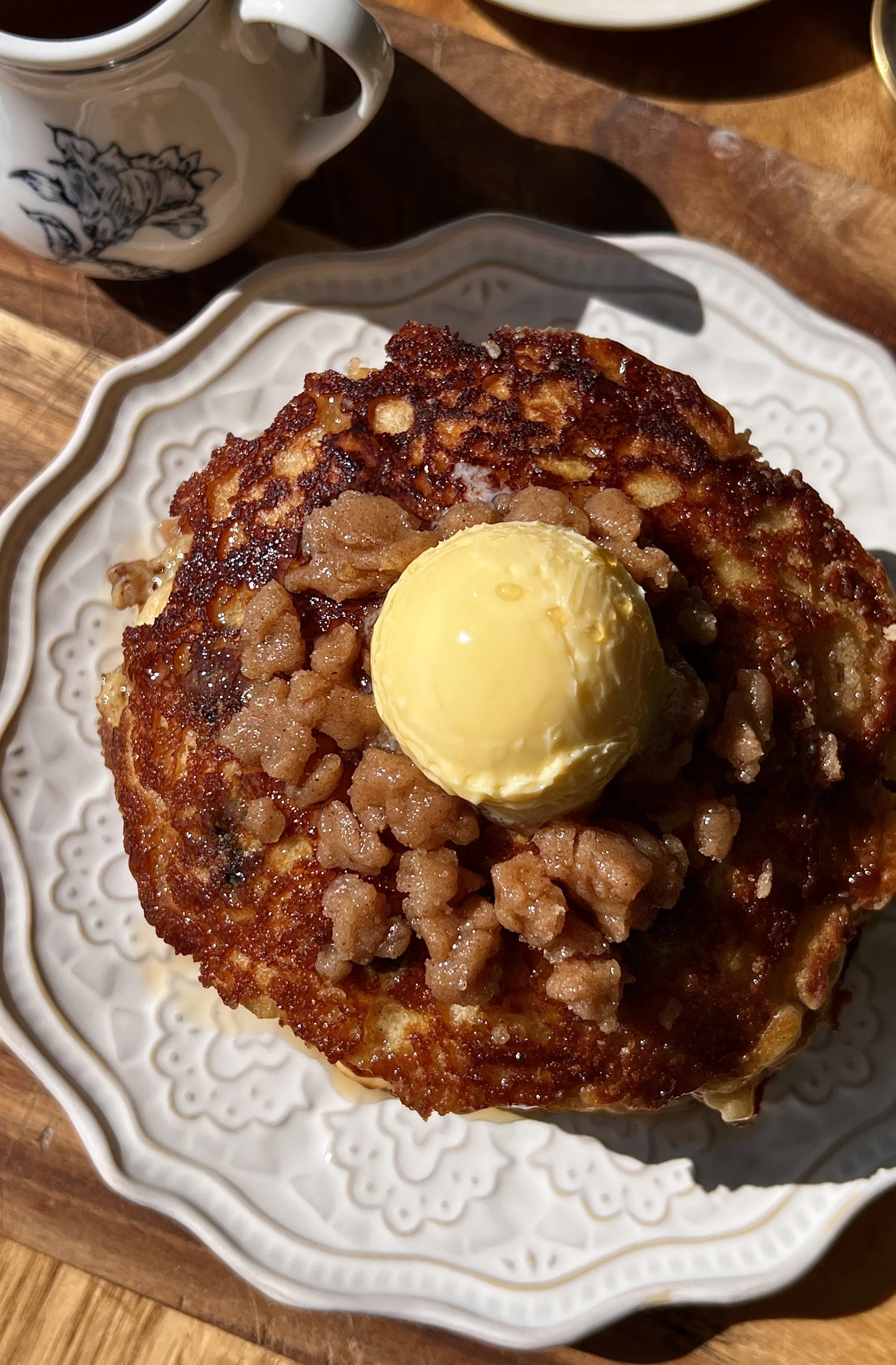 Soft and fluffy brown butter blueberry muffin pancakes with a perfectly golden exterior and warm cinnamon streusel caramelized on top served warm with a pat of butter, maple syrup, and a hot cup of coffee.