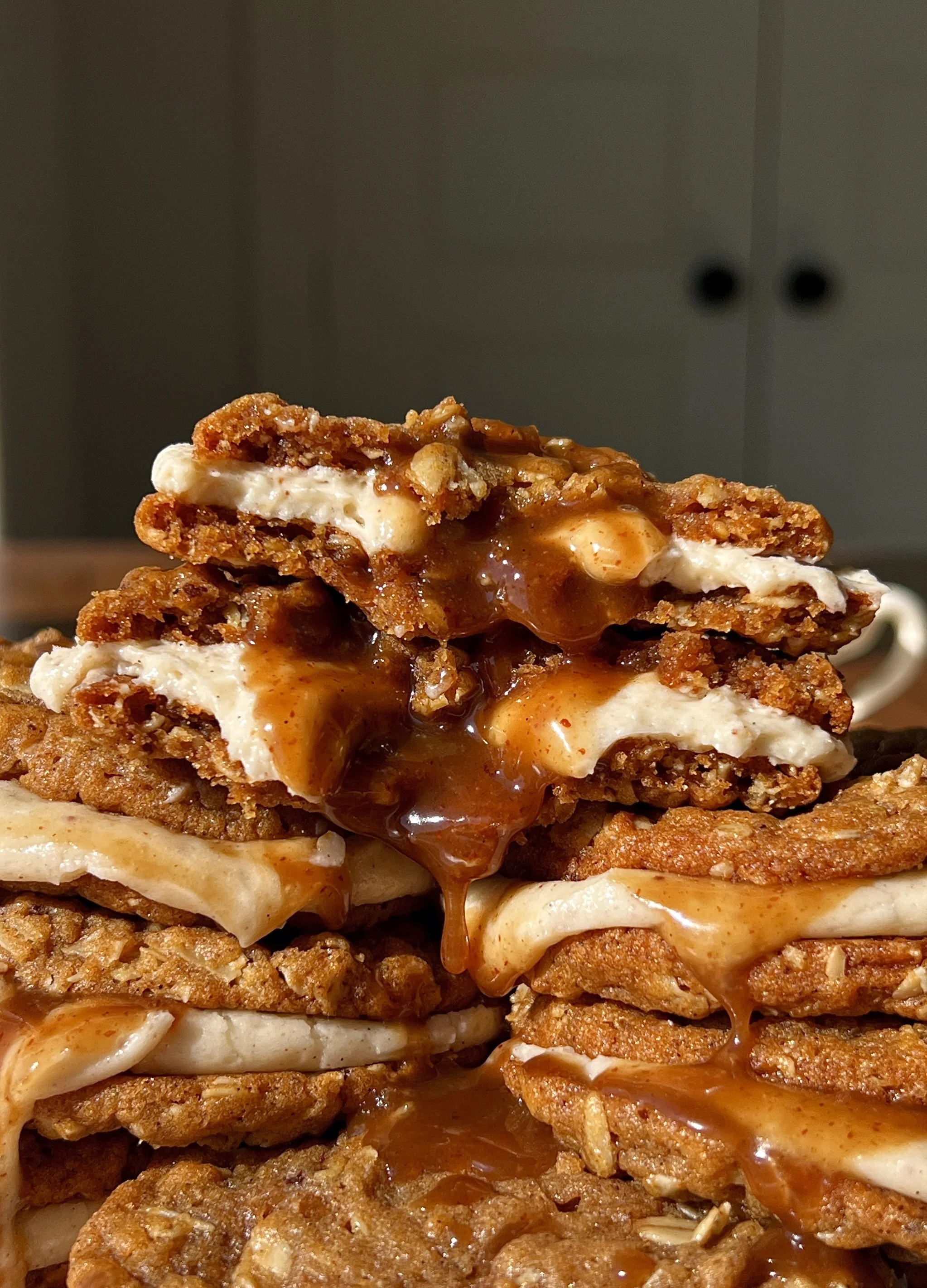 Brown butter sweet potato oatmeal cream pie with a bite taken out showing the soft chewy spiced sweet potato oatmeal cookie and lush brown butter cream cheese filling with salted maple caramel melting inside.