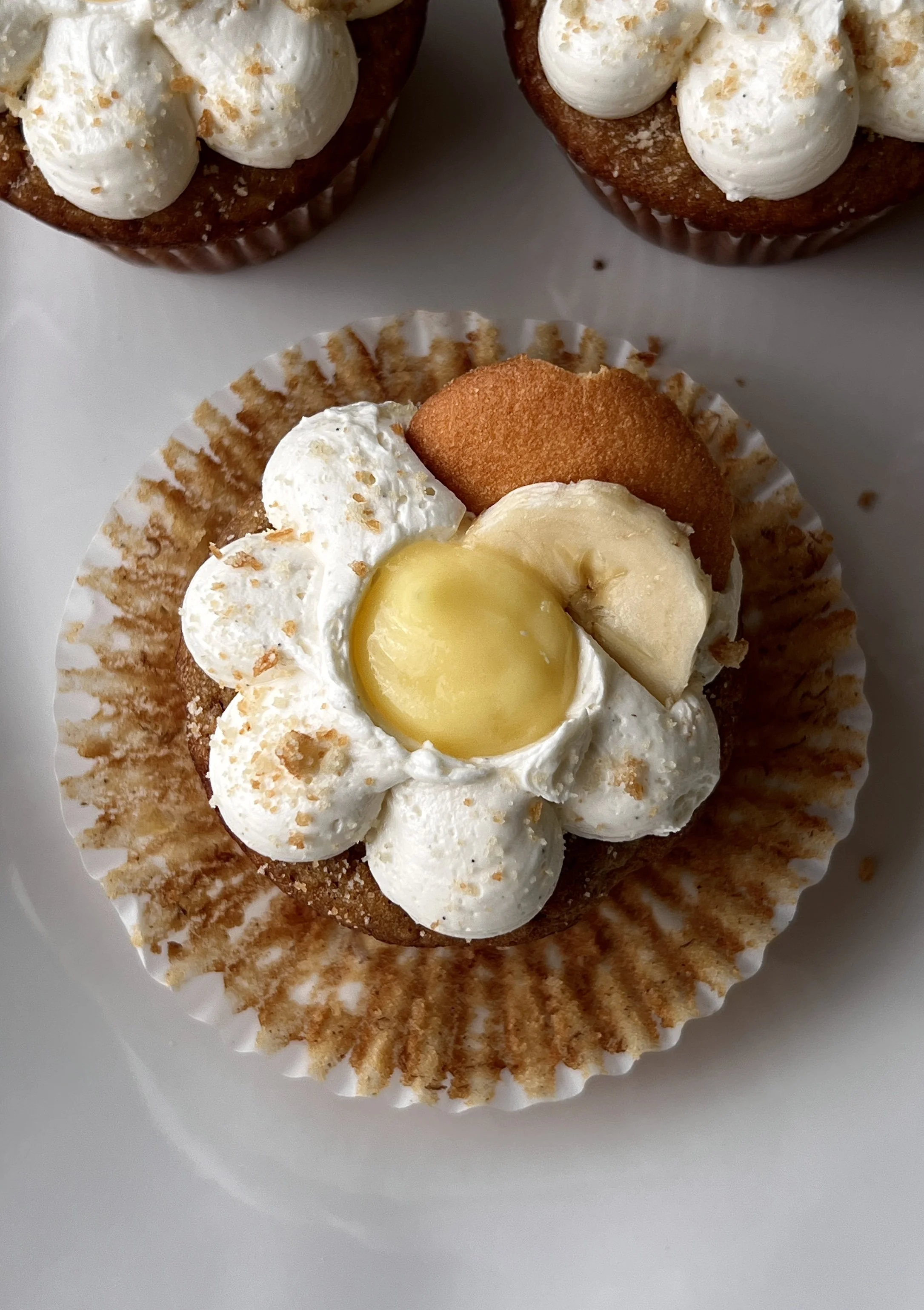 Close-up of a brown butter banana pudding cupcake filled with classic vanilla pudding and topped with light and fluffy whipped buttercream and crushed Nilla wafers.