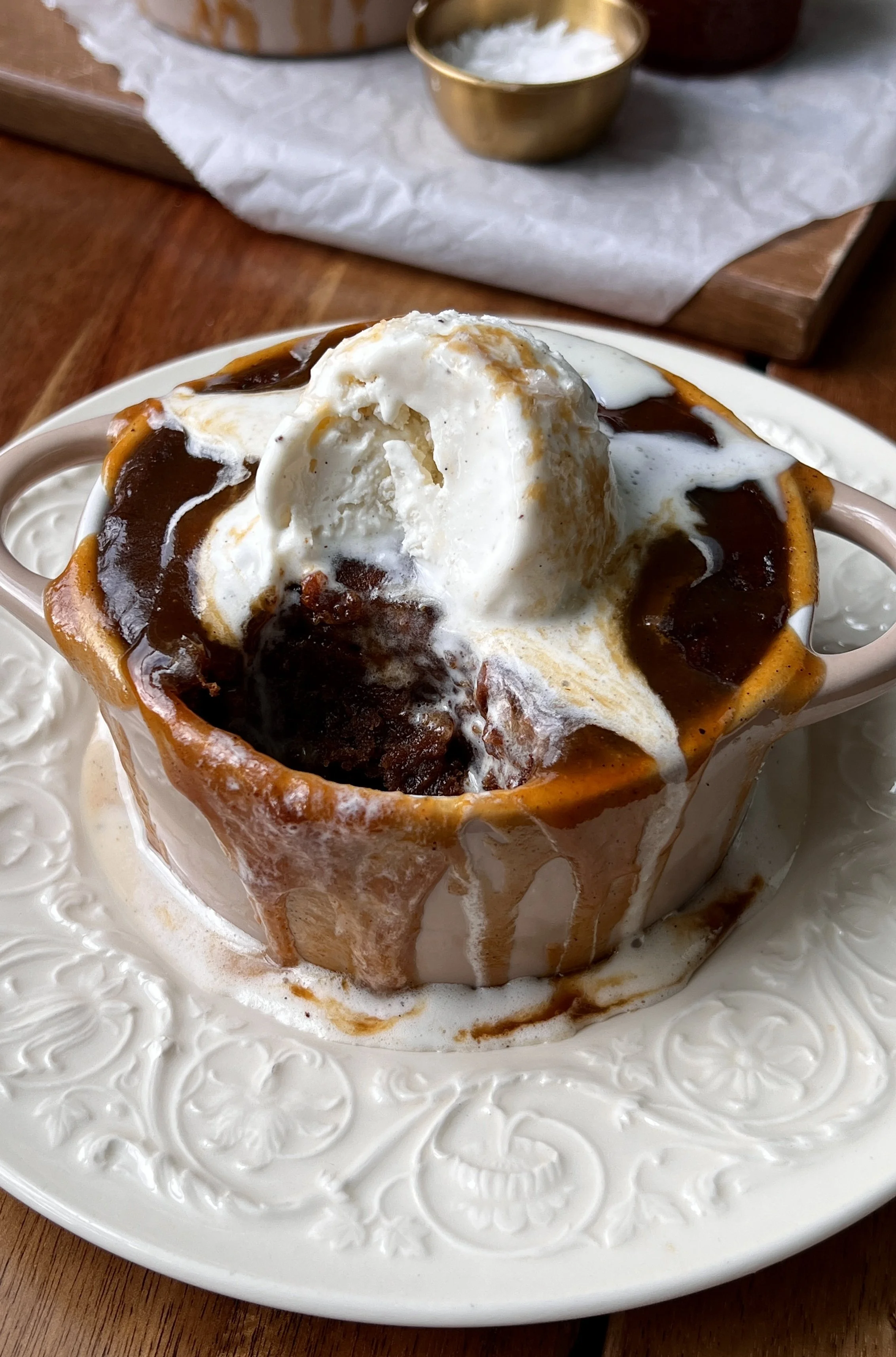 Close-up of Sweet Potato Sticky Toffee Puddings topped with melting vanilla ice cream and drizzled with warm toffee sauce